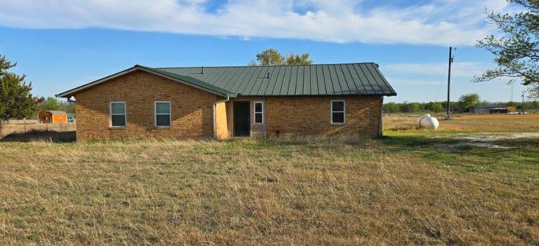 Back of house featuring brick siding, a lawn, and