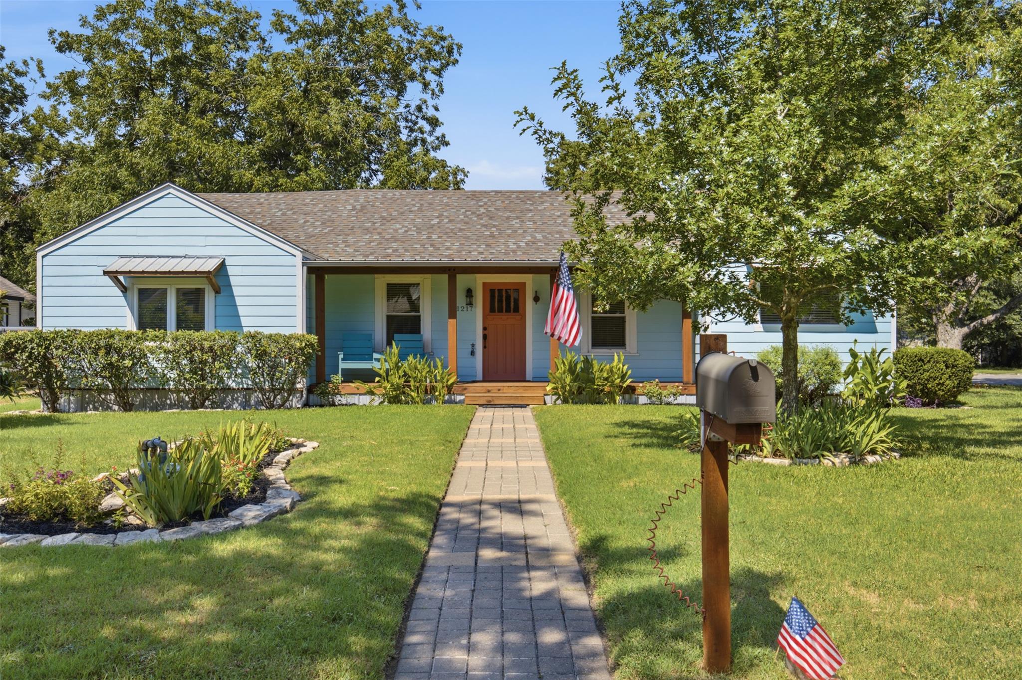 A welcoming light blue home boasts a charming fro