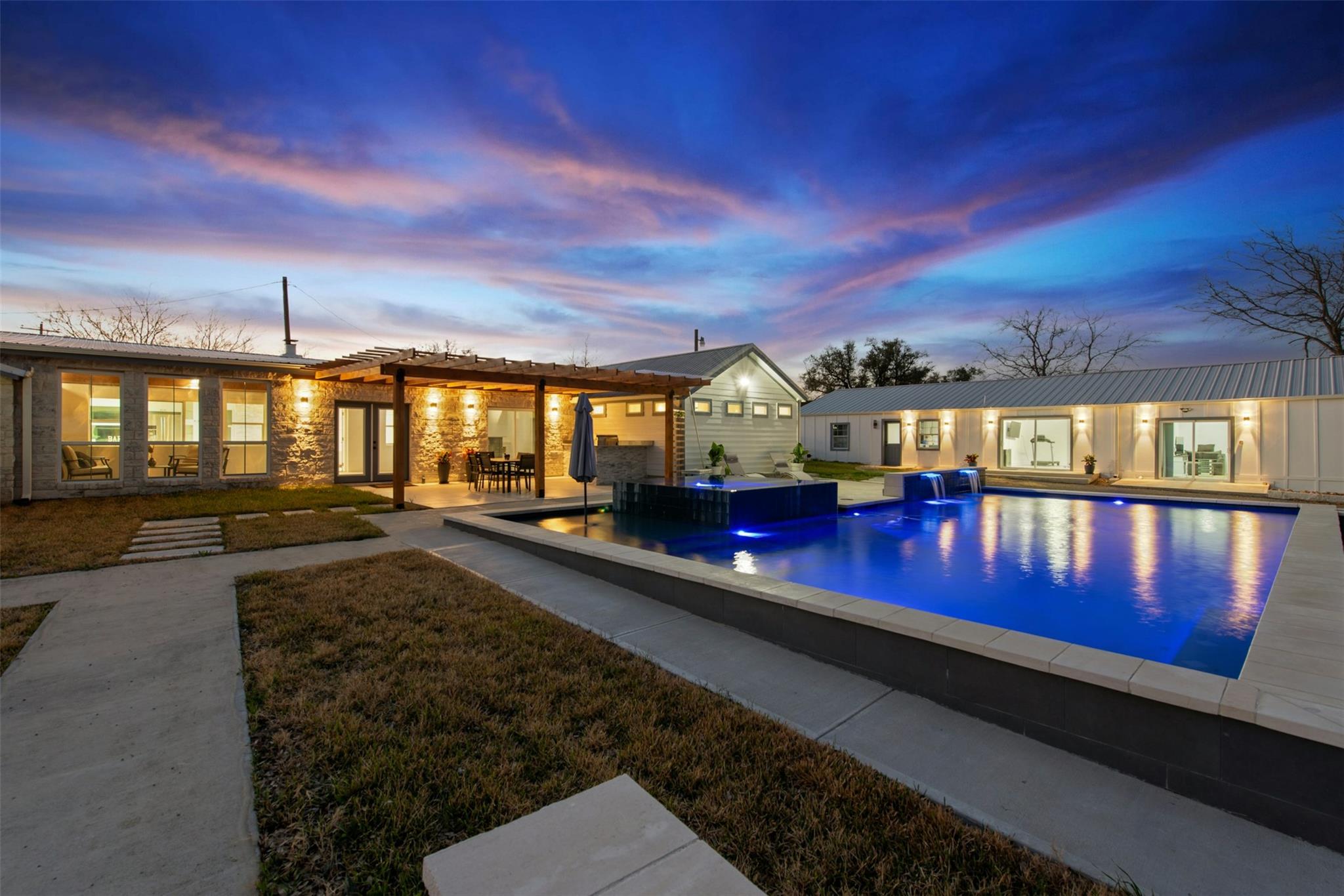 Pool at dusk featuring a jacuzzi, a patio, an out