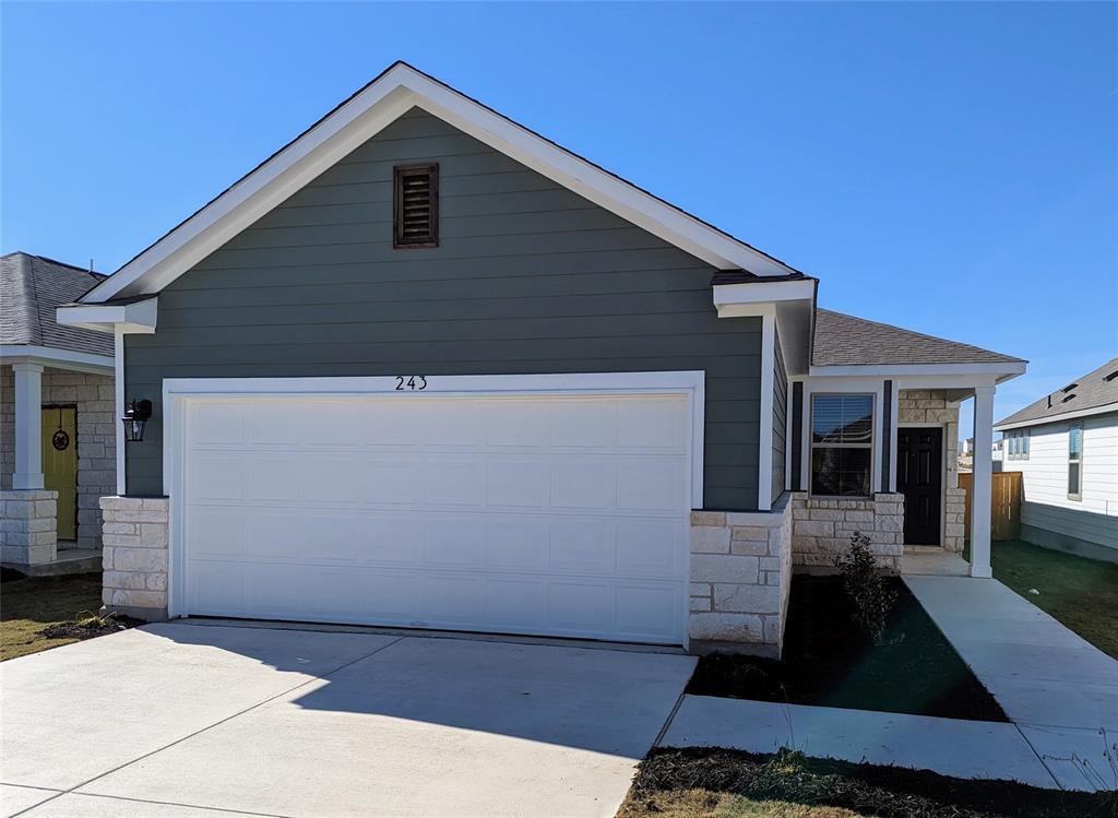 Single story home with stone siding, driveway, an