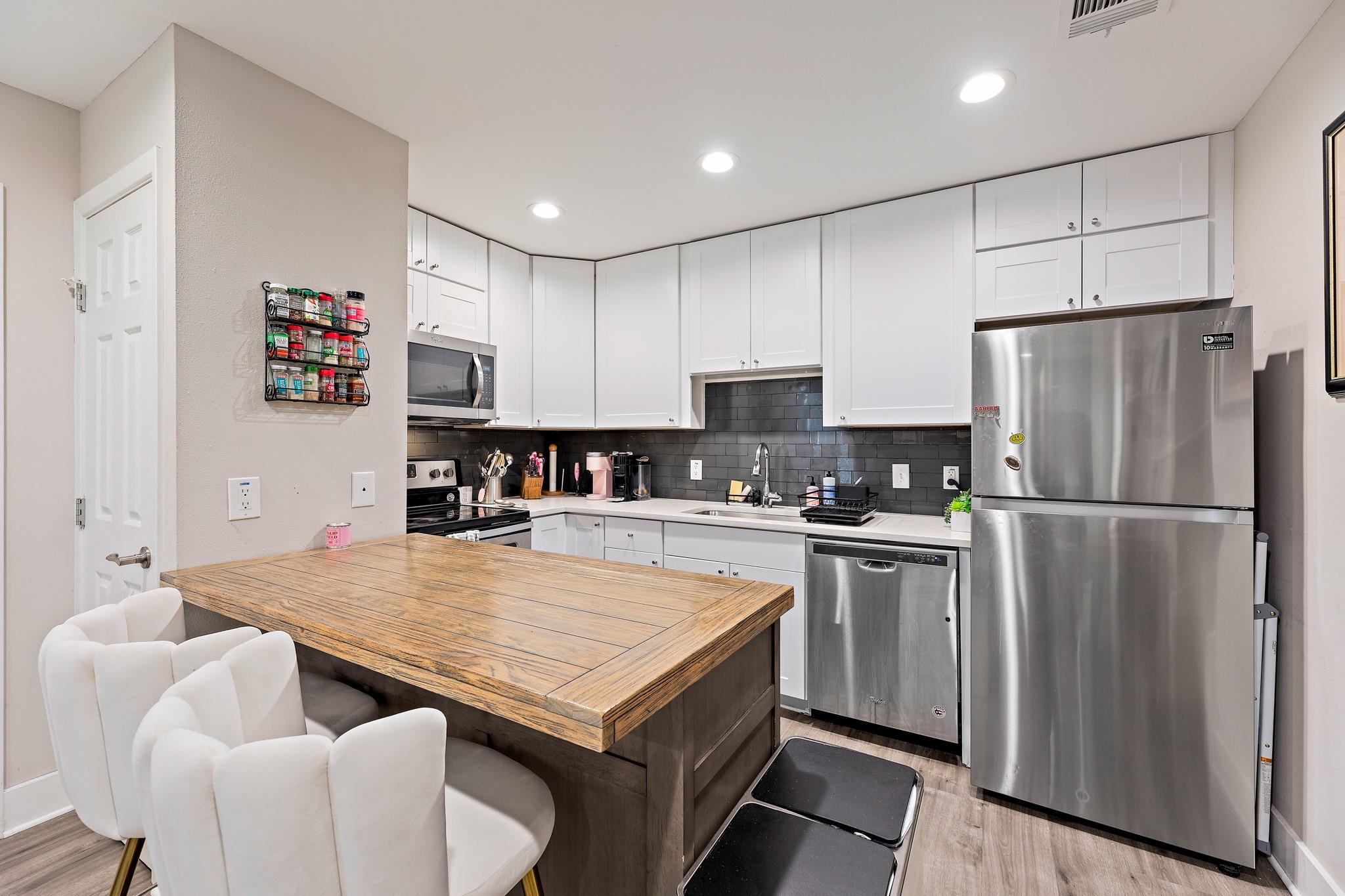The kitchen features white cabinetry, a dark subw