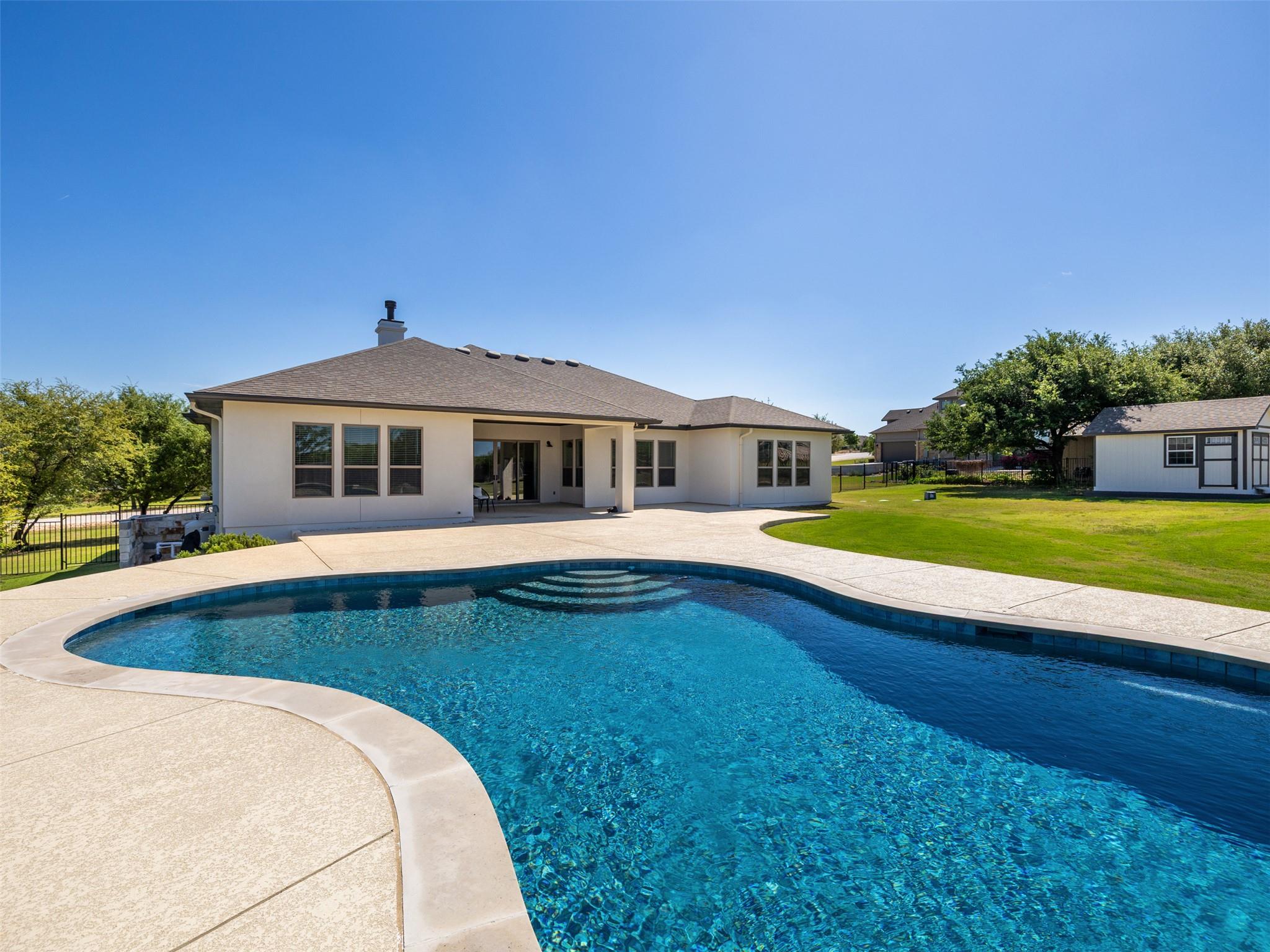 View of swimming pool with patio surround and a f