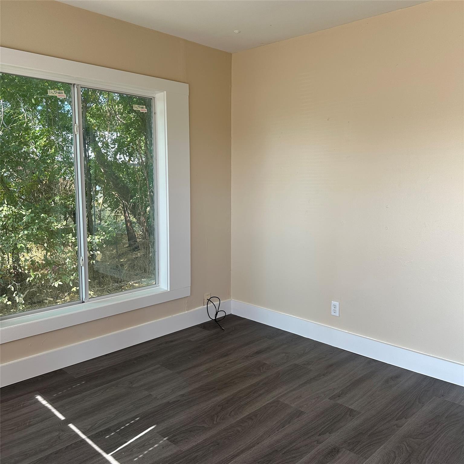 Room featuring dark plank flooring, light beige w