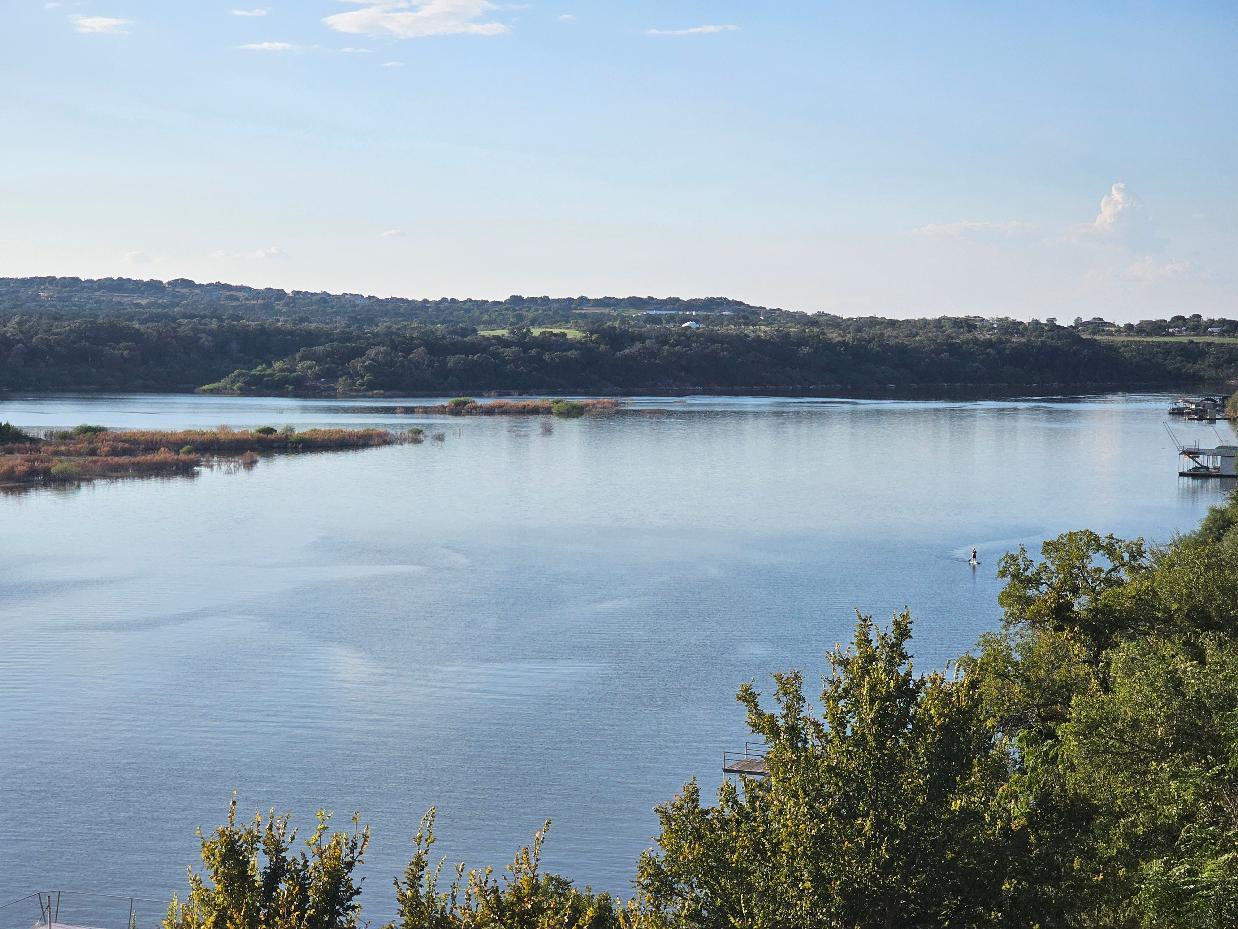 A tranquil lake view extends past lush greenery t