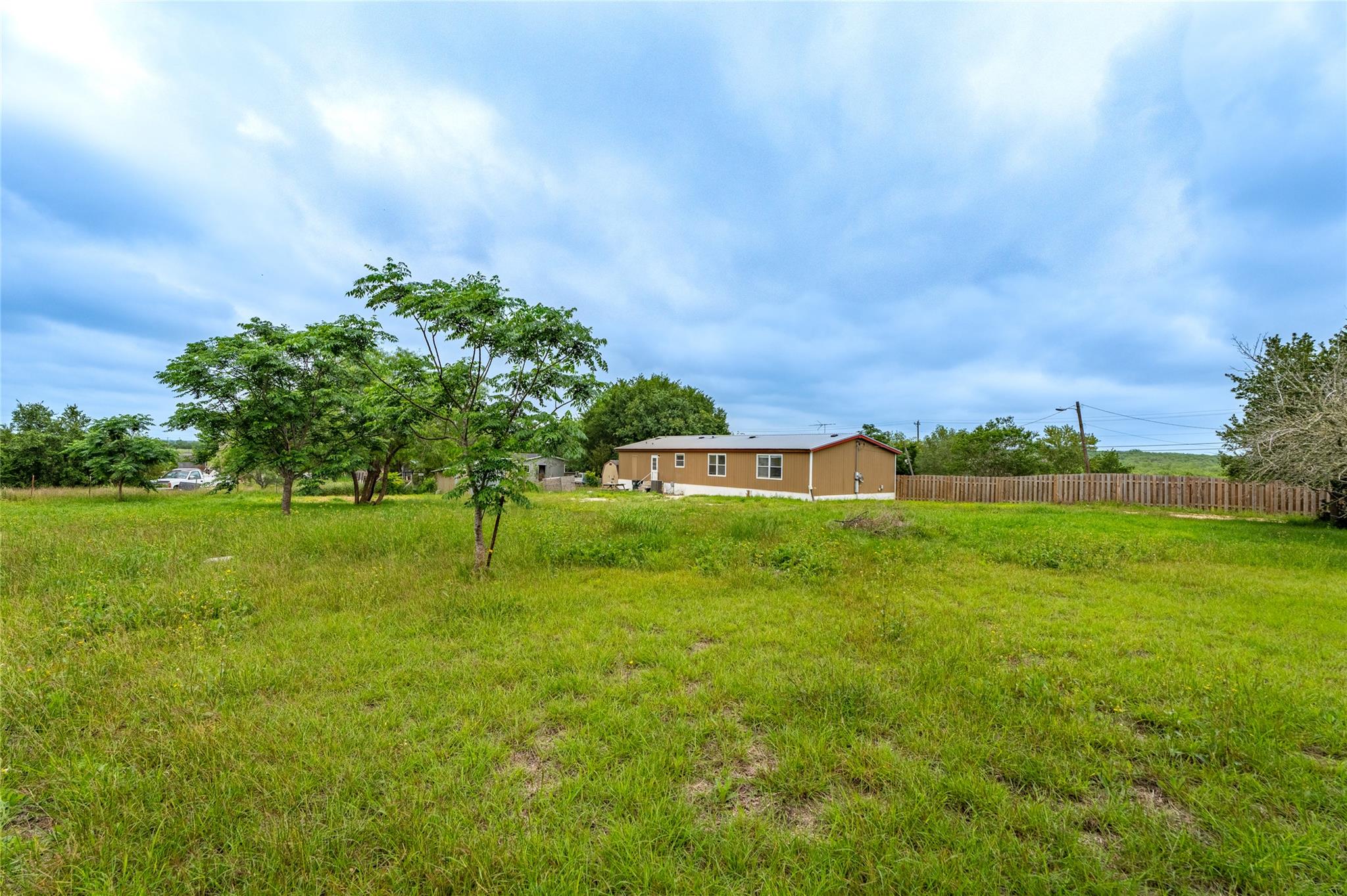 Expansive grassy lot featuring mature trees and a