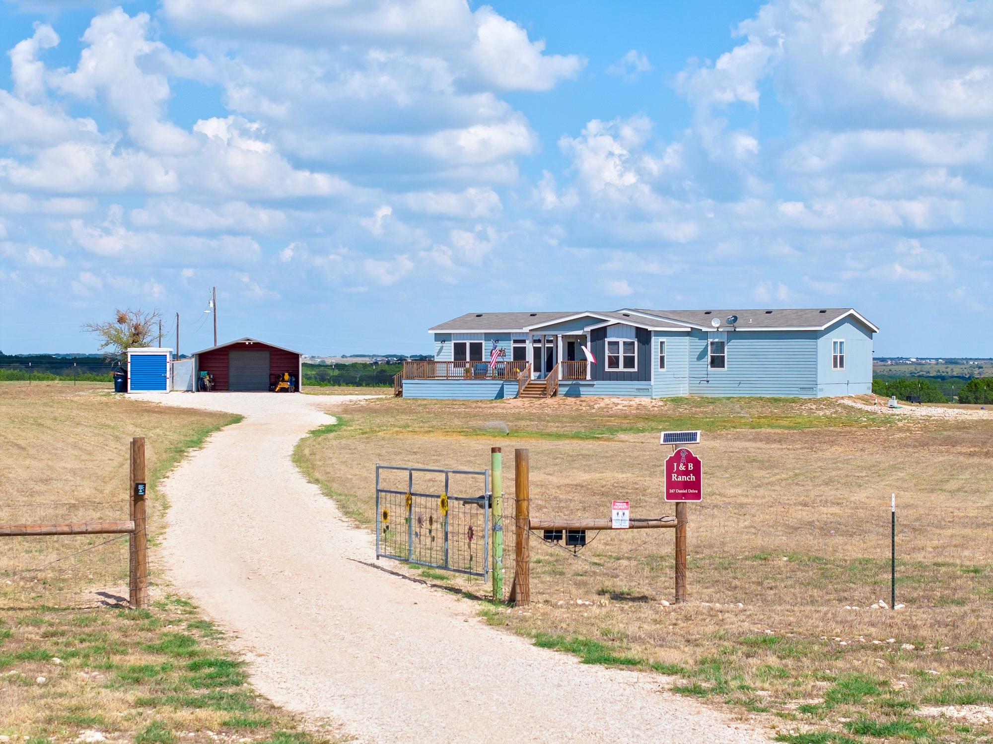 A long gravel driveway leads to a welcoming rural