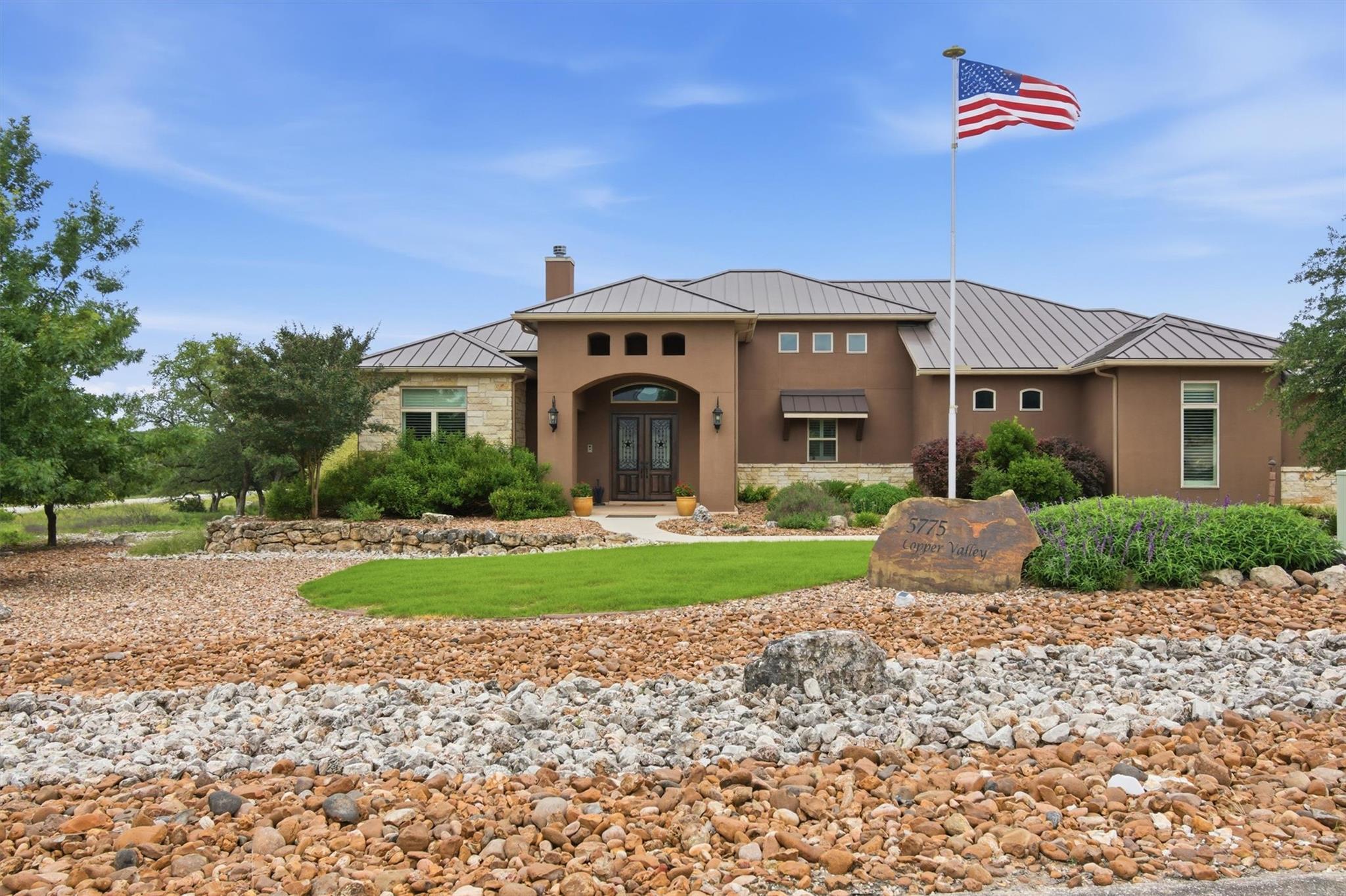 Stucco and stone exterior featuring a metal roof