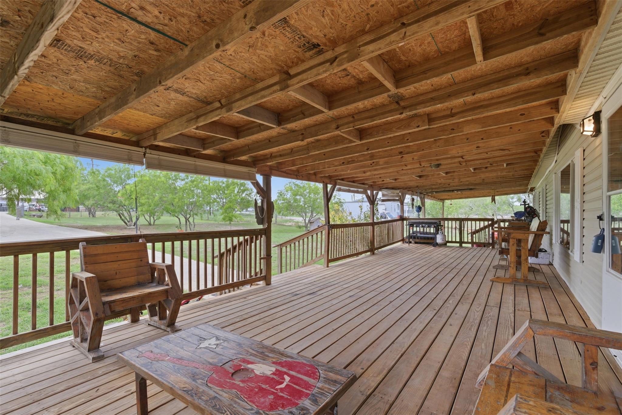 Expansive covered porch featuring wood decking, a