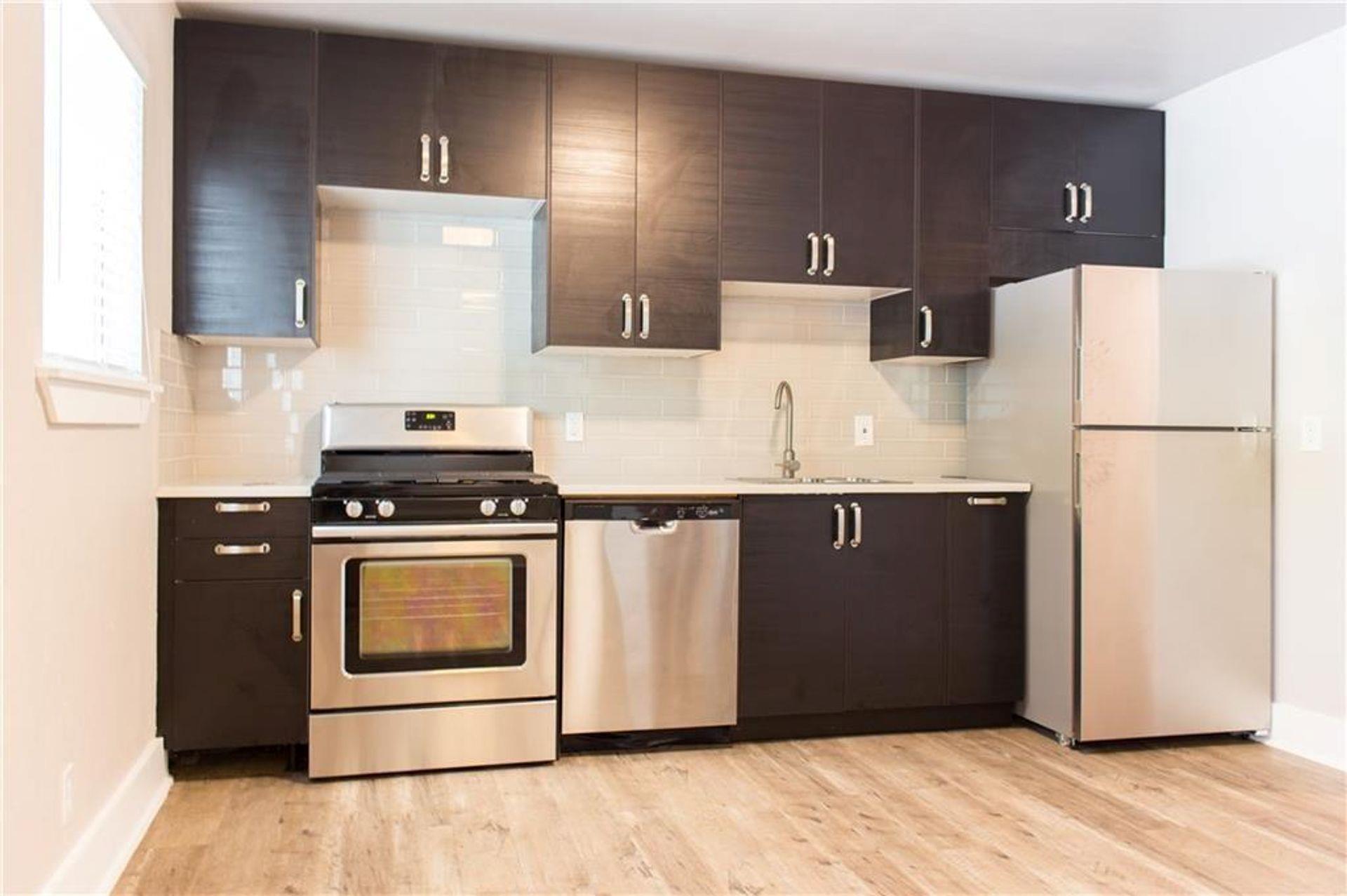 The kitchen features dark wood cabinetry with sta