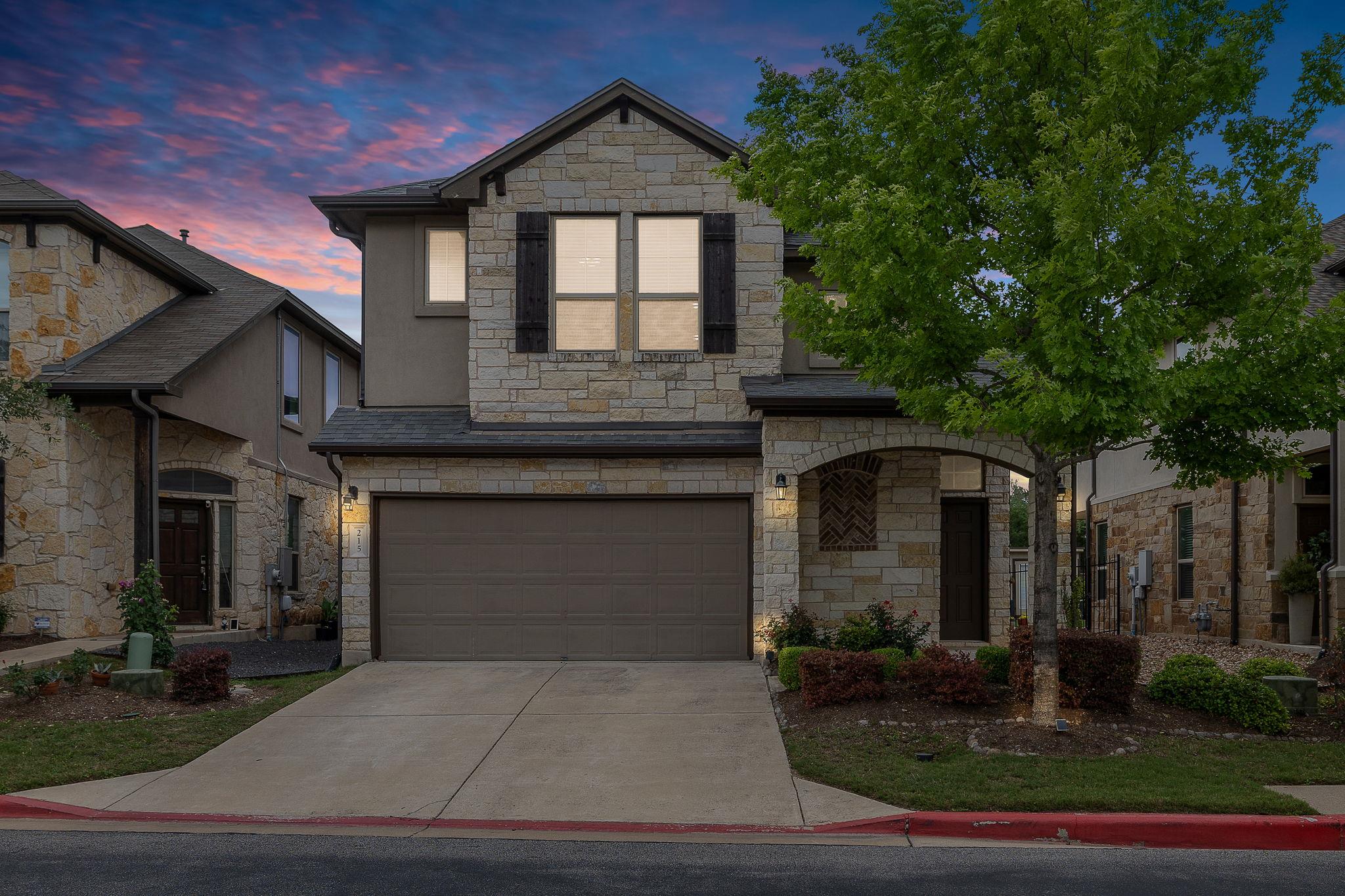 Stone and stucco exterior featuring a two-car gar