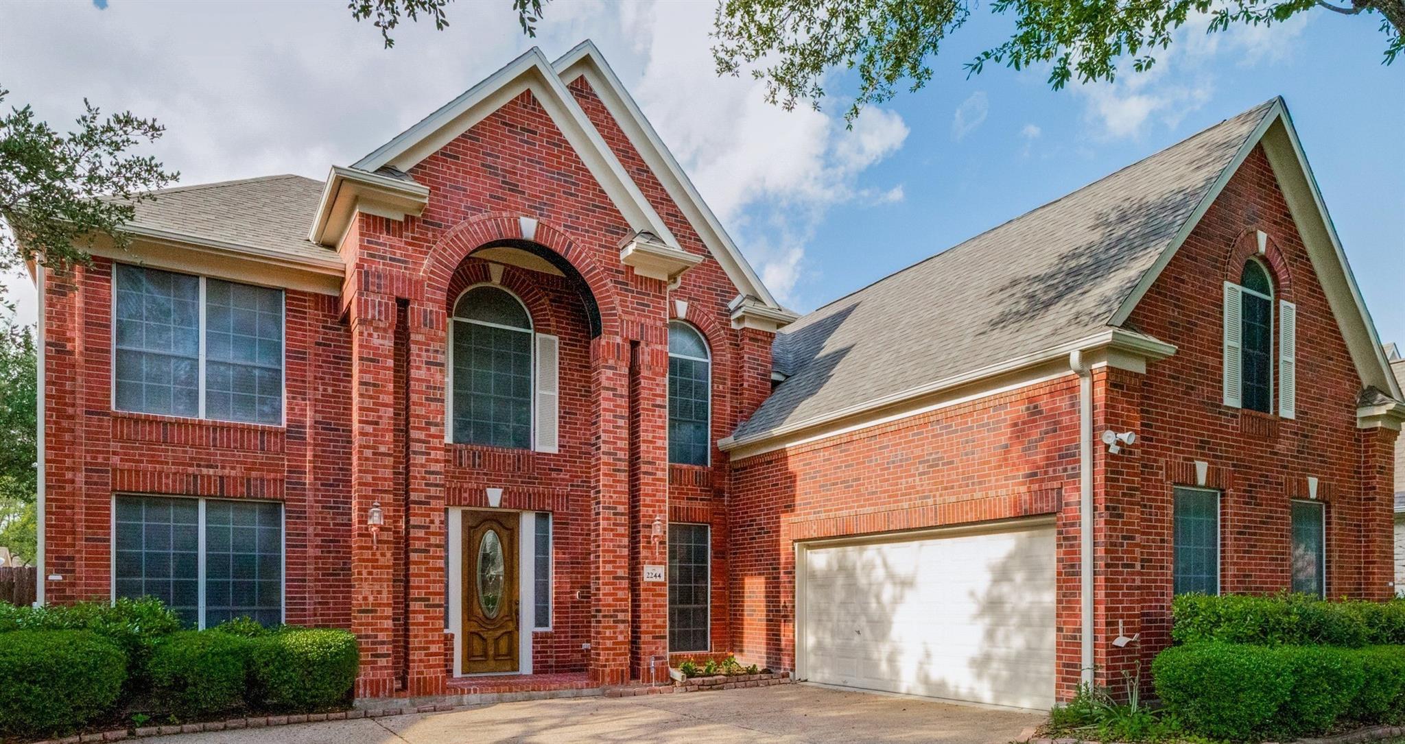 Two-story brick exterior featuring an arched entr