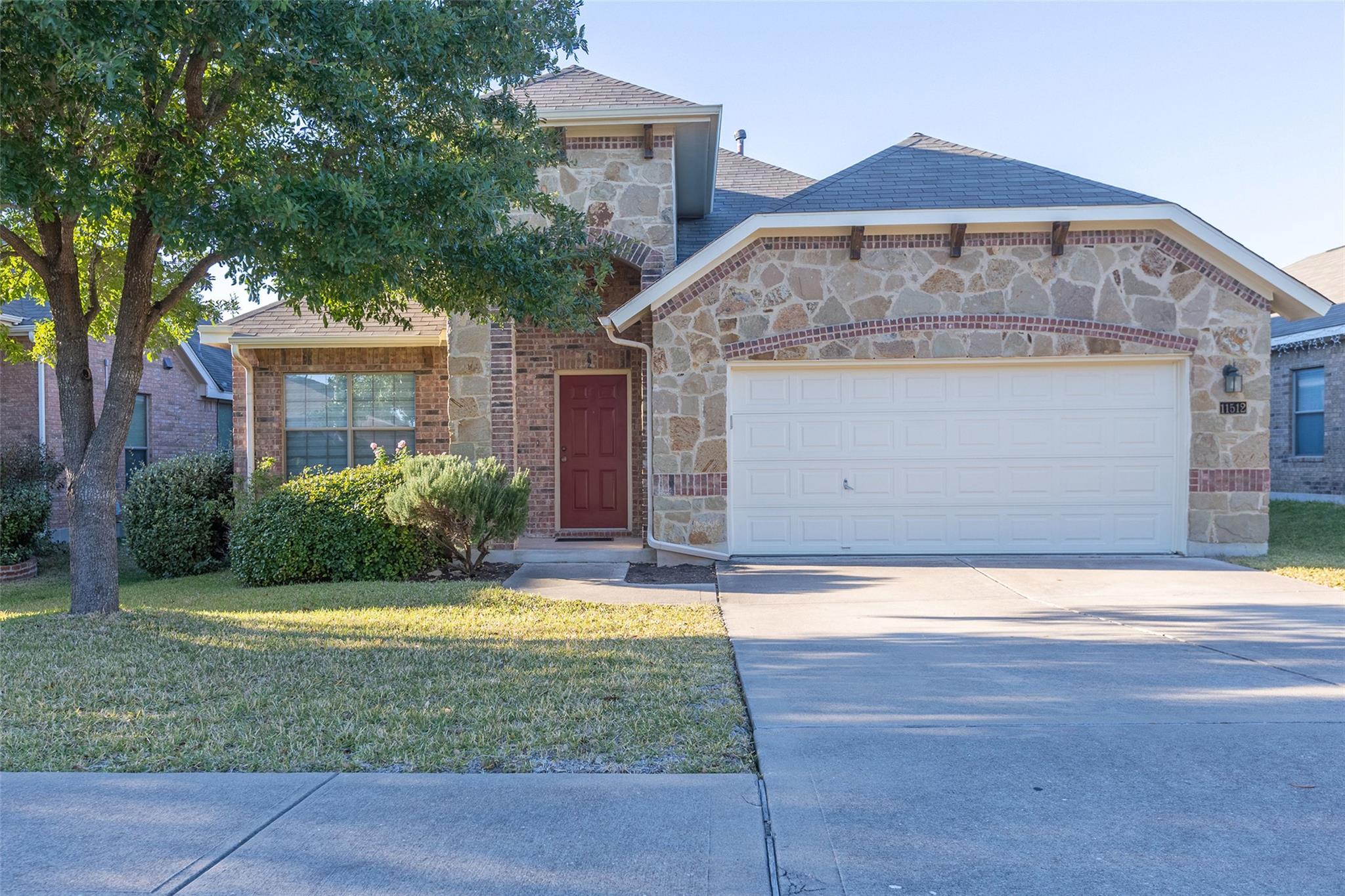 Stone and brick facade with a red entry door, an 