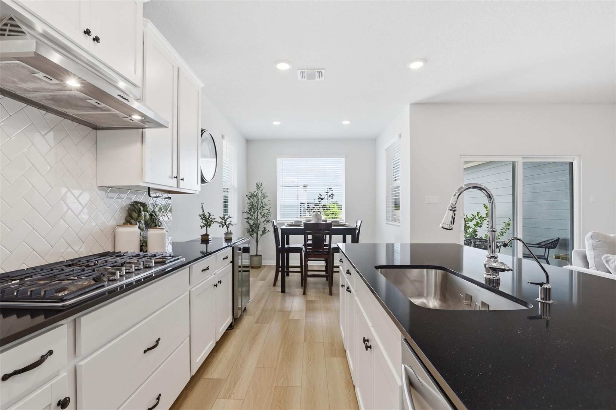 Bright kitchen featuring white cabinetry, dark co