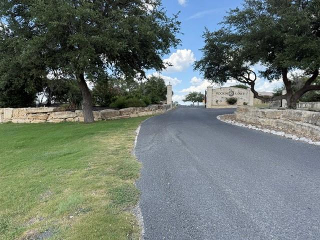 Paved entrance road framed by mature trees and na
