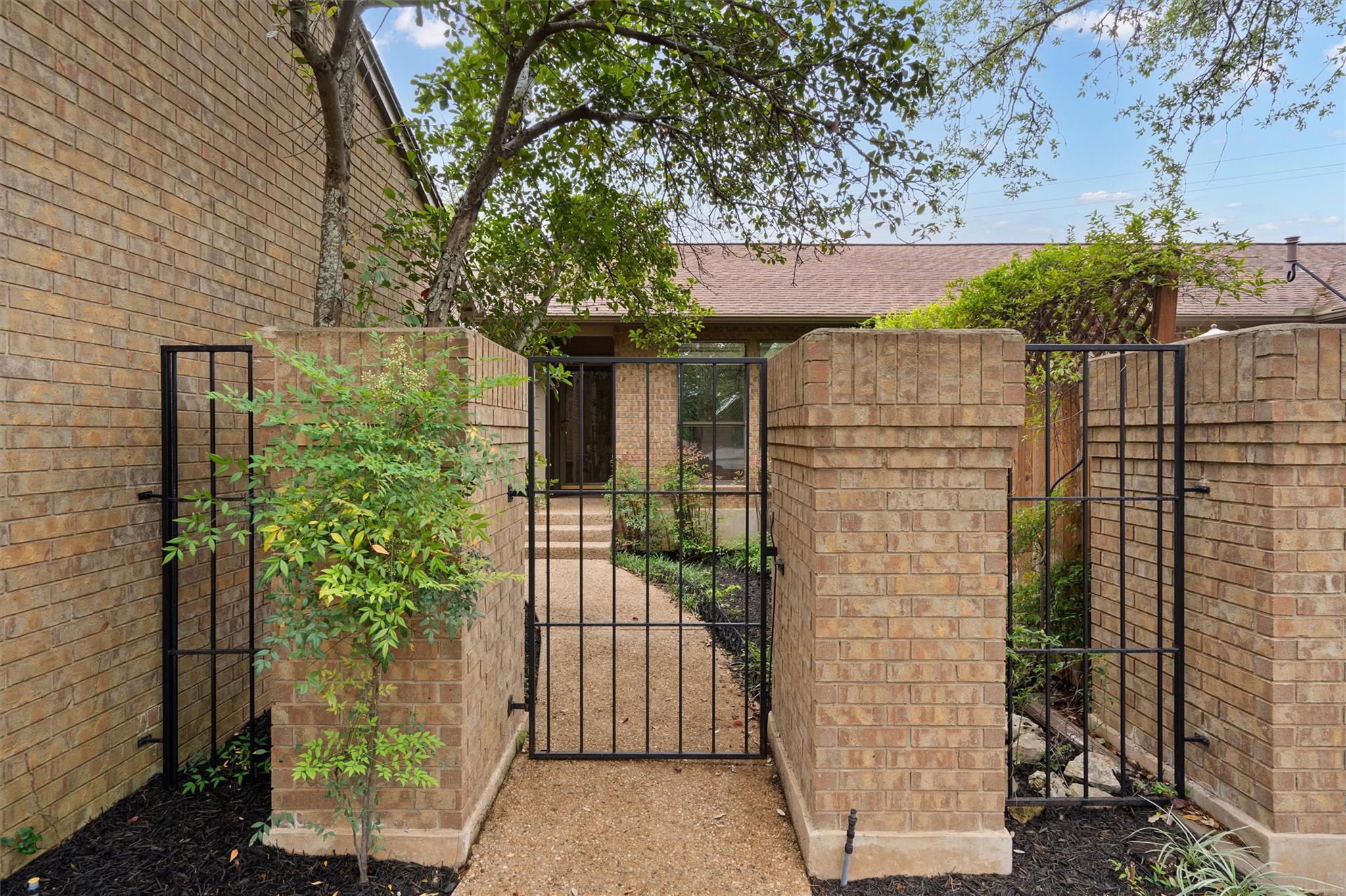 Gated entryway featuring brick pillars and black 
