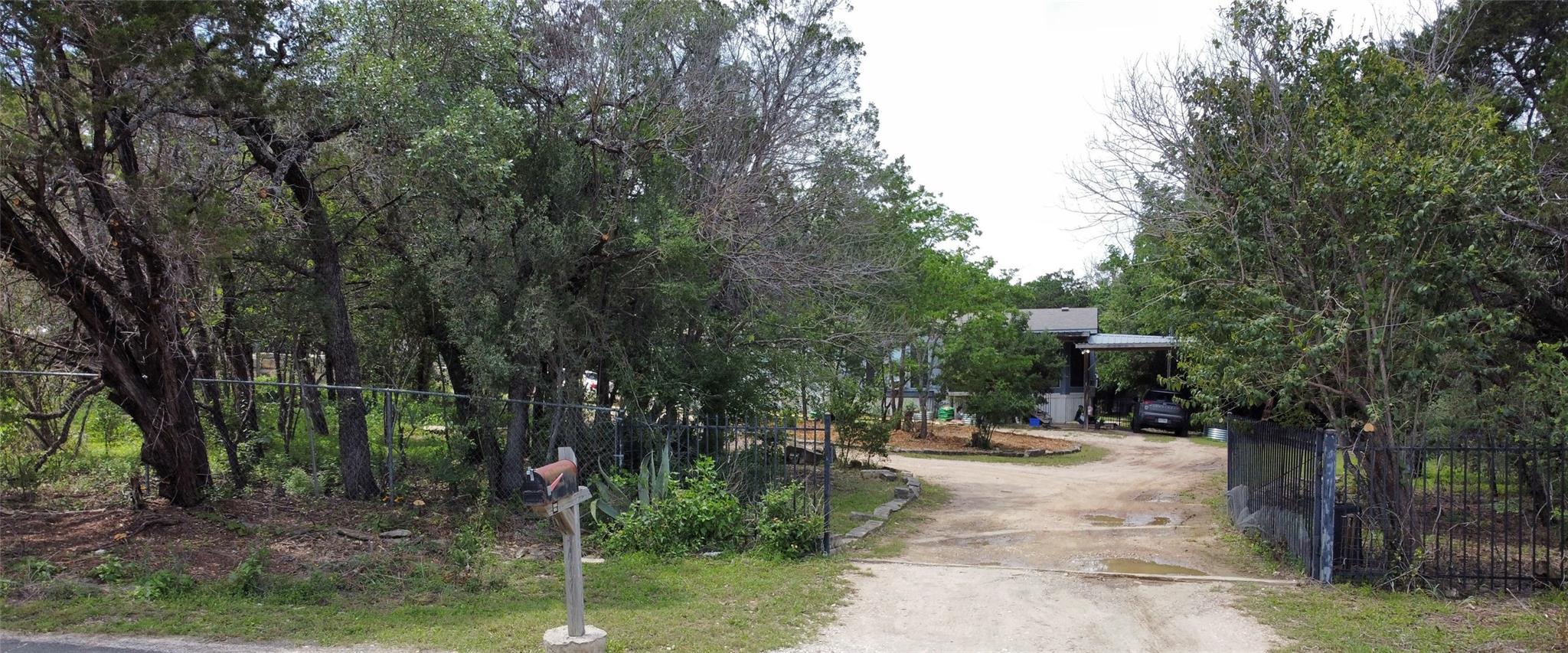 Gated property entrance with a gravel driveway, m