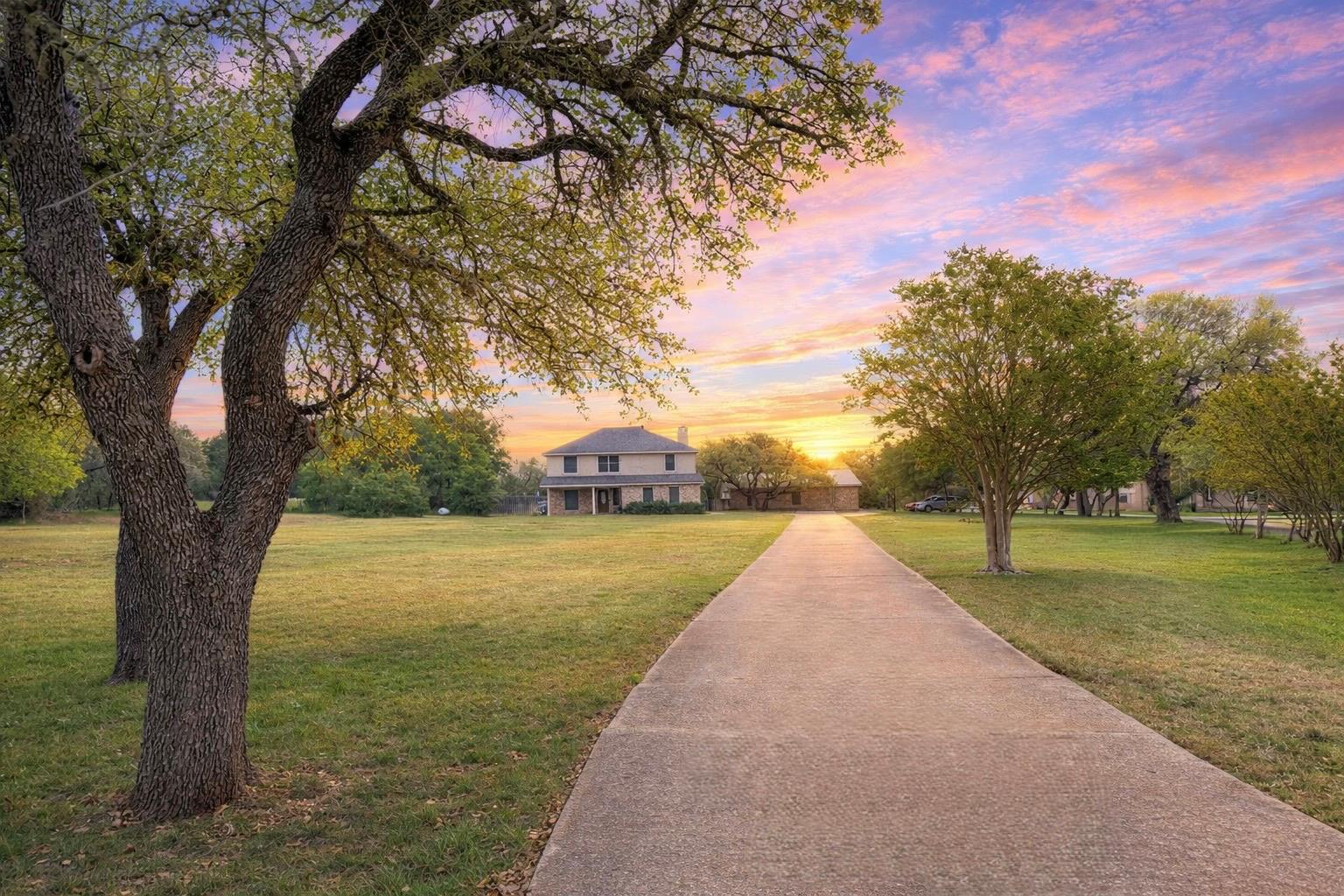 Long paved driveway approaching a two-story resid