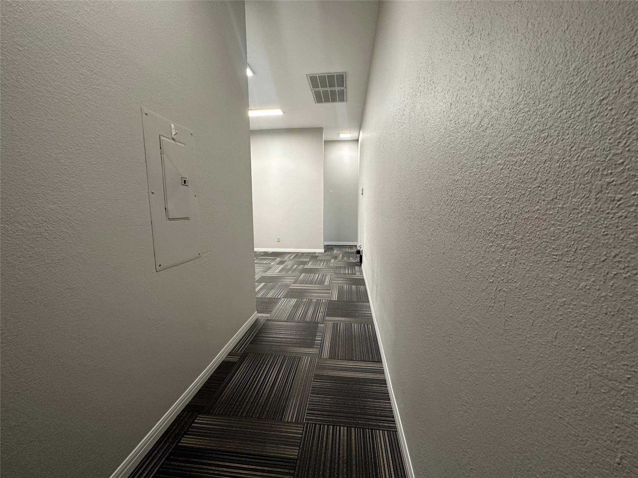 Hallway featuring patterned carpet flooring, neut