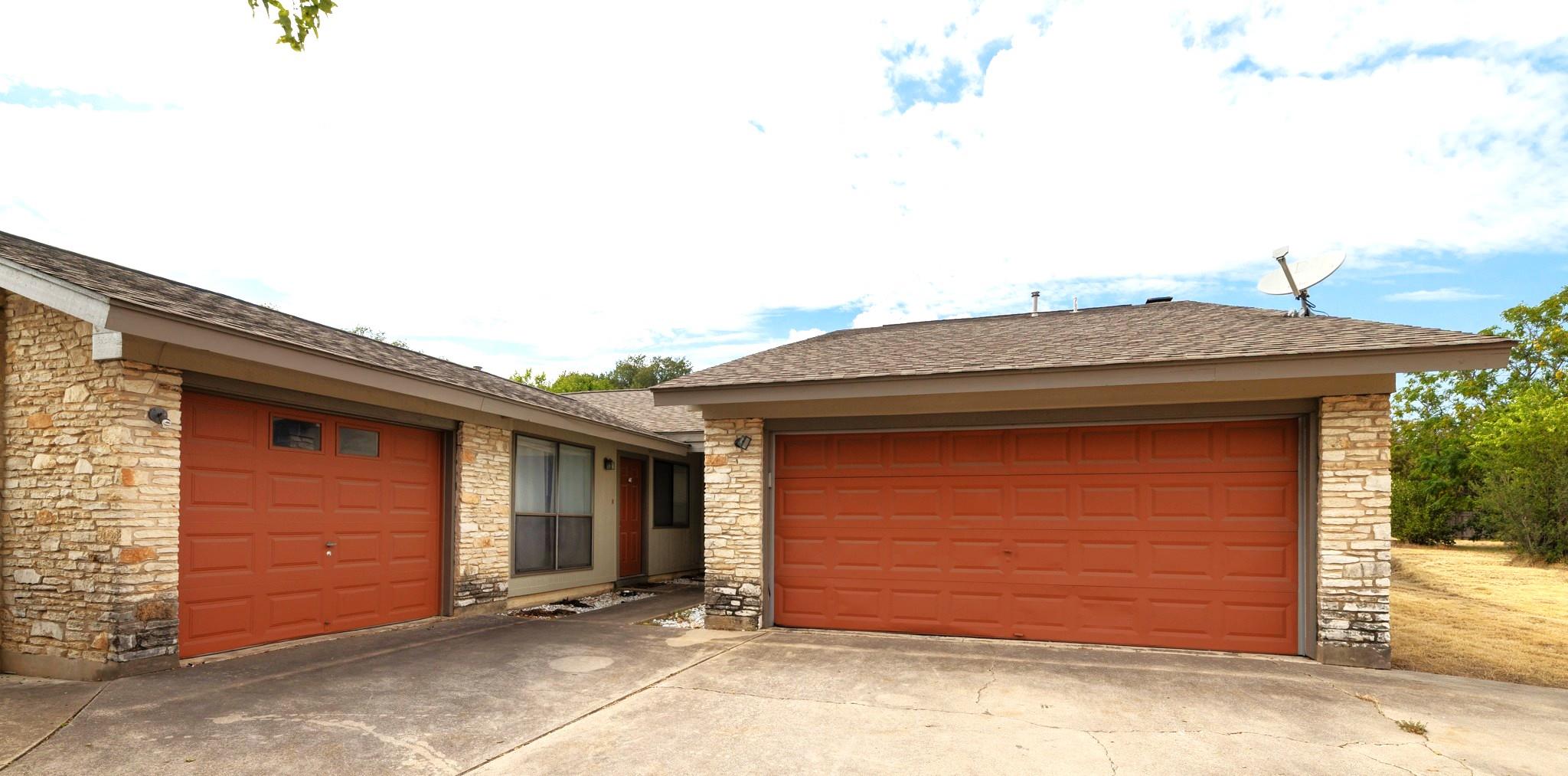 A spacious concrete driveway leads to multiple ga