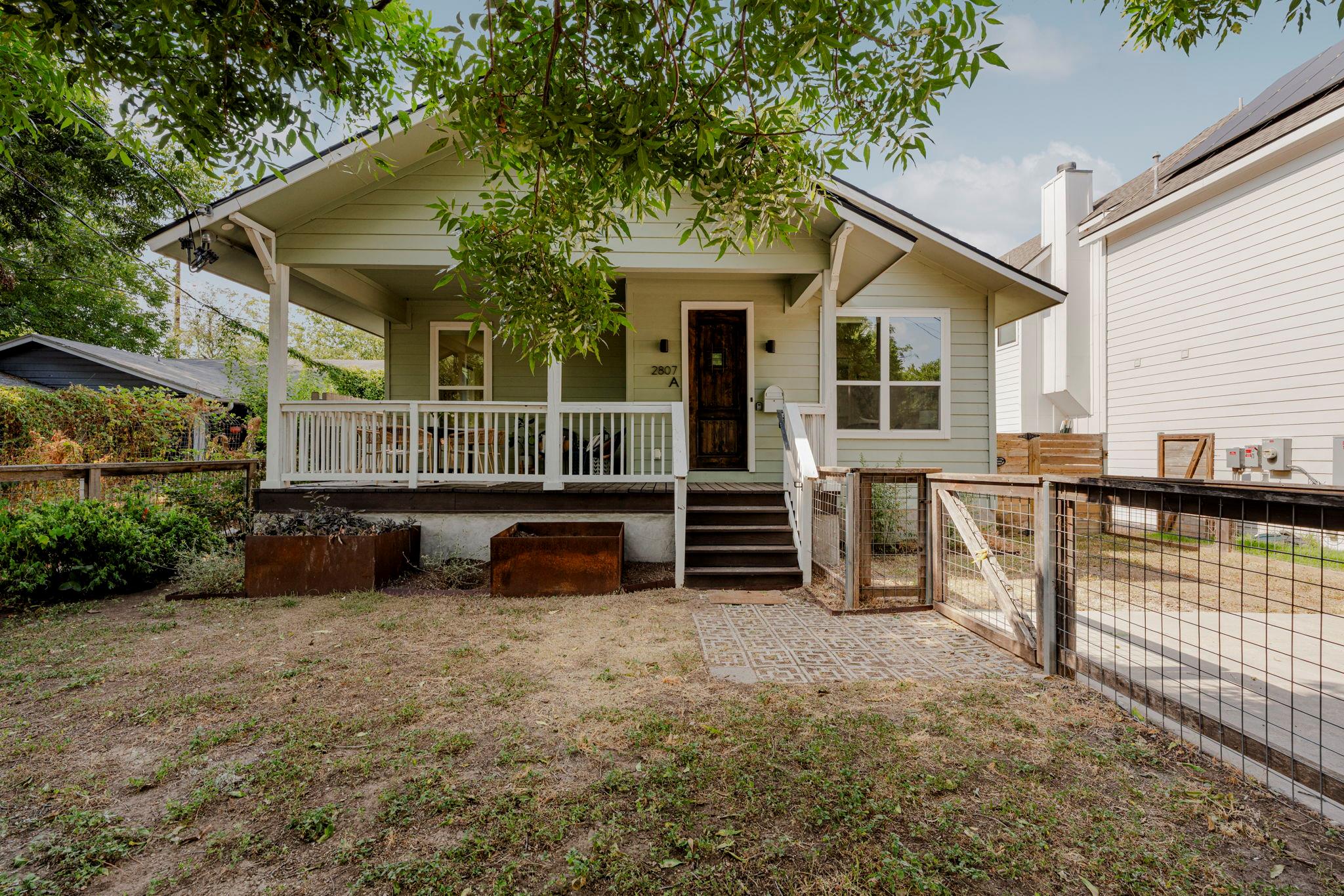 Welcoming front porch and fenced yard highlight t