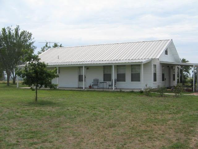 White exterior with a metal roof, featuring a cov