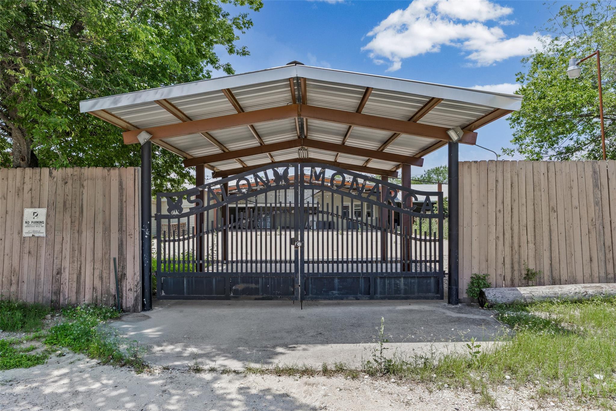 Ornate wrought iron gate set within a wood fence,