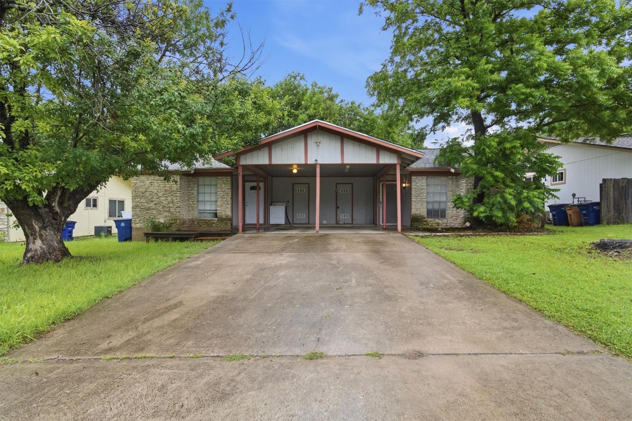 Duplex exterior featuring a covered carport, ston