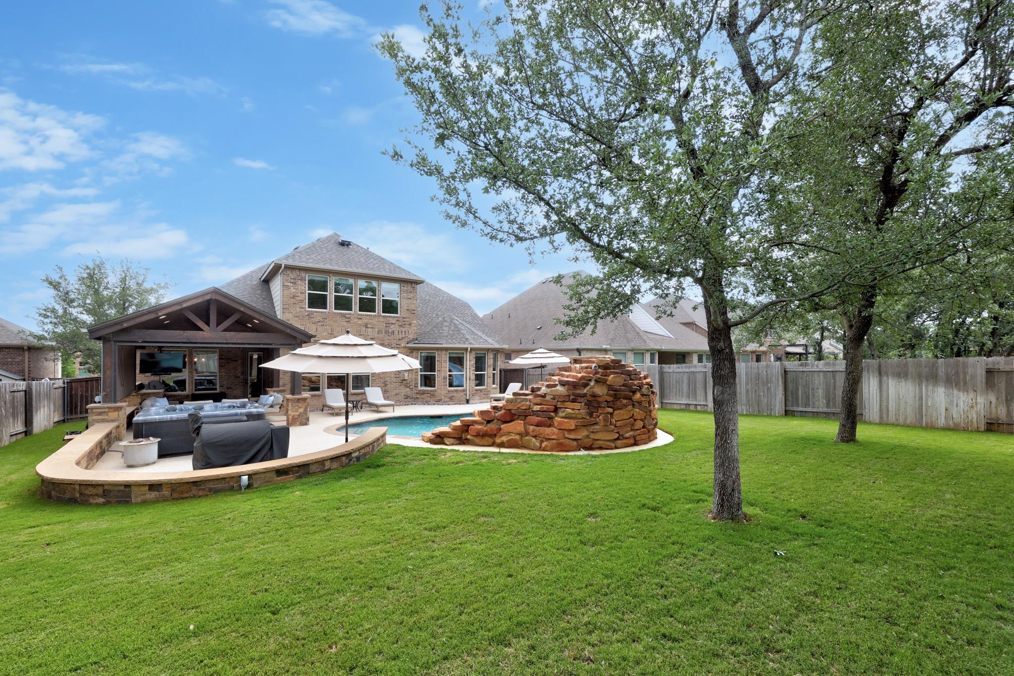 Expansive backyard featuring a stone patio, cover