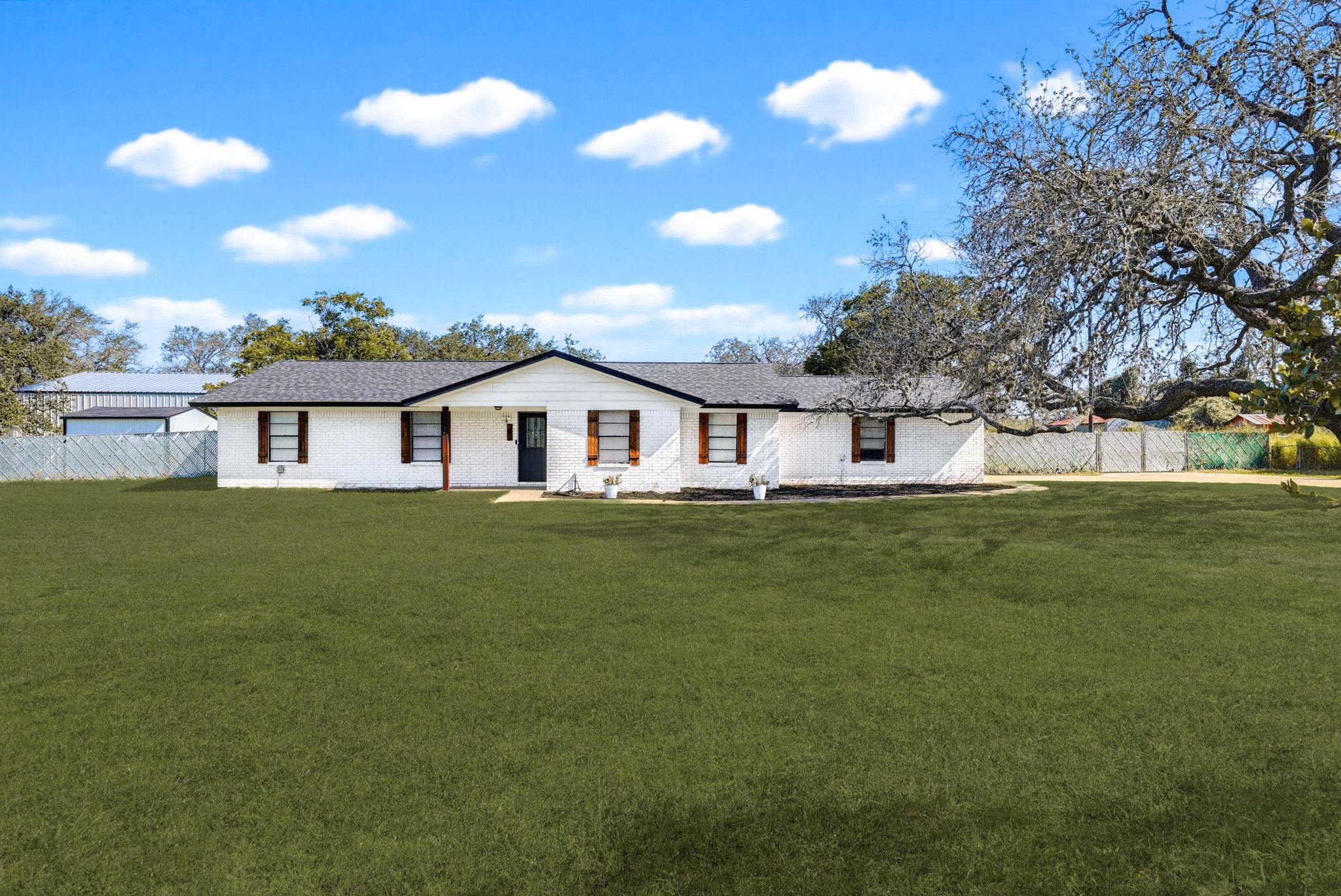 A classic white brick ranch home presents a welco