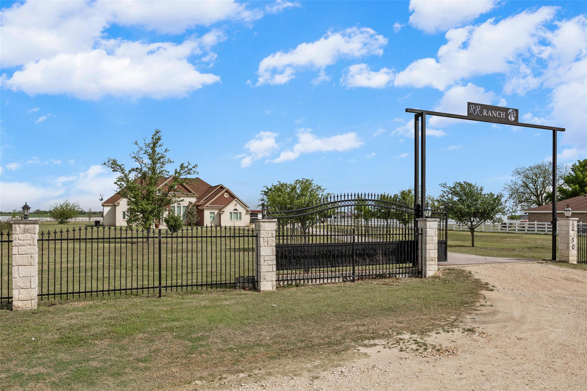 Wrought iron gate with stone pillars and an overh