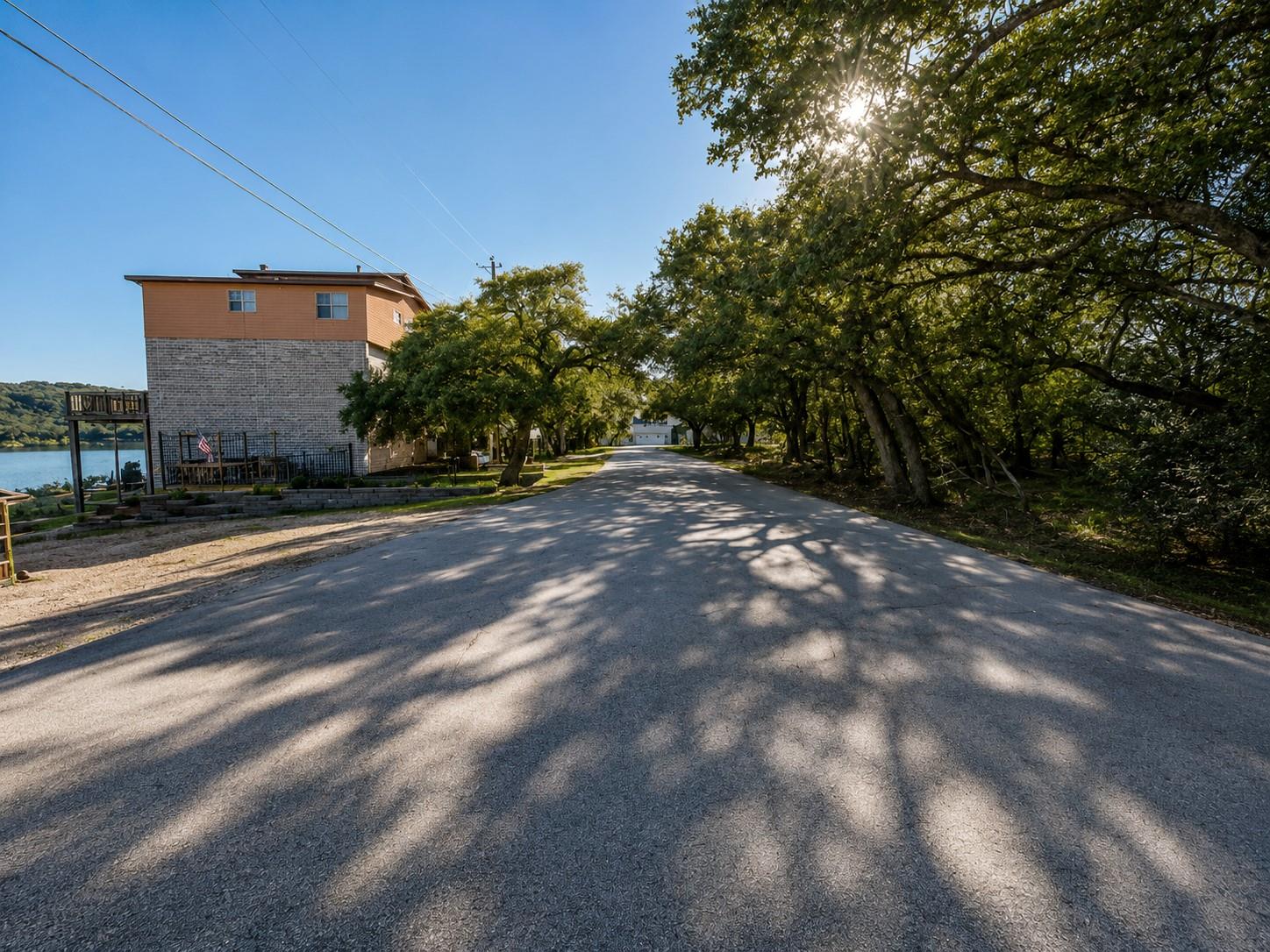 Mature trees shade a paved neighborhood road lead
