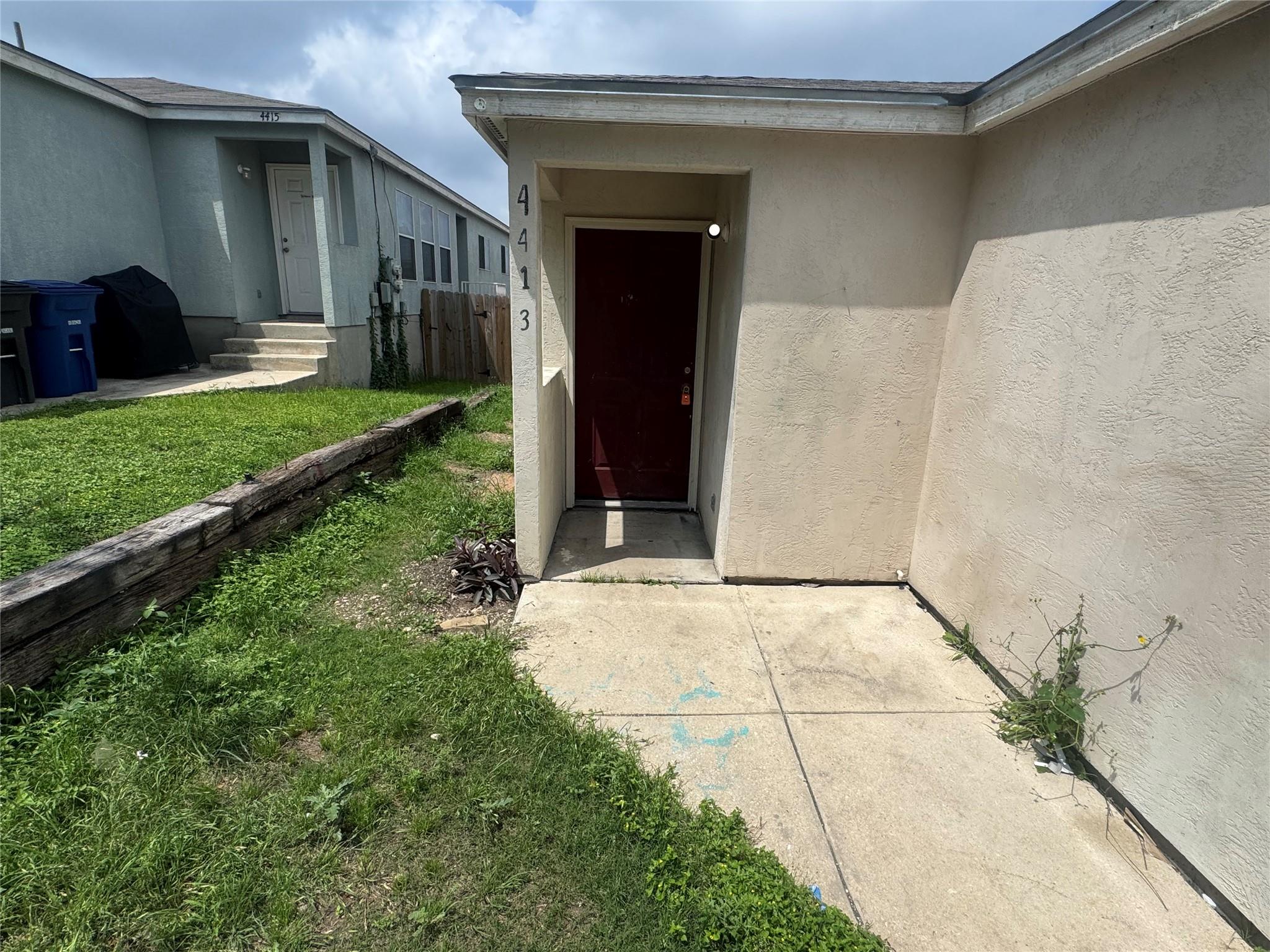 Entryway featuring a red door, stucco exterior, a