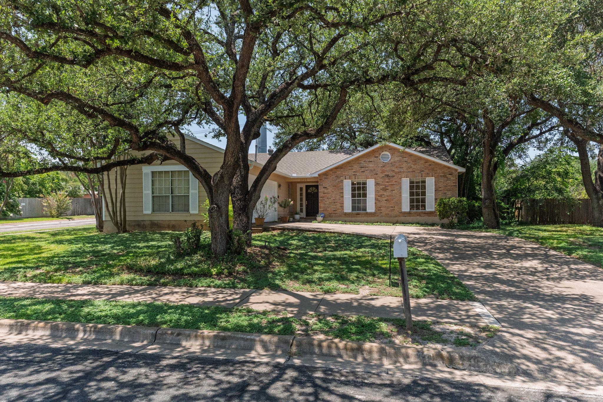 Mature shade trees frame this classic single-stor
