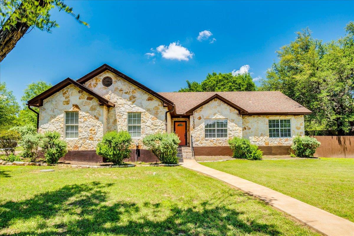 Stone facade residence with a brown shingle roof,