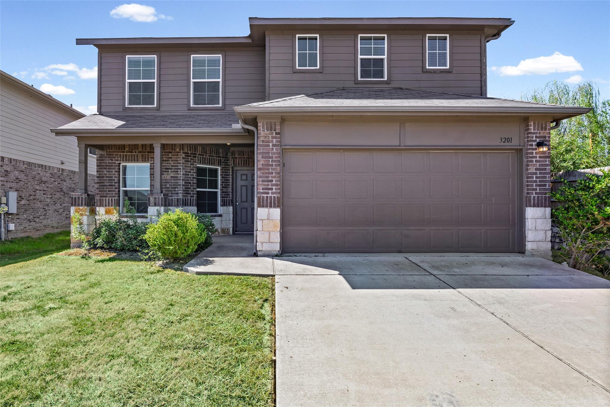 A concrete driveway leads toward a two-story home
