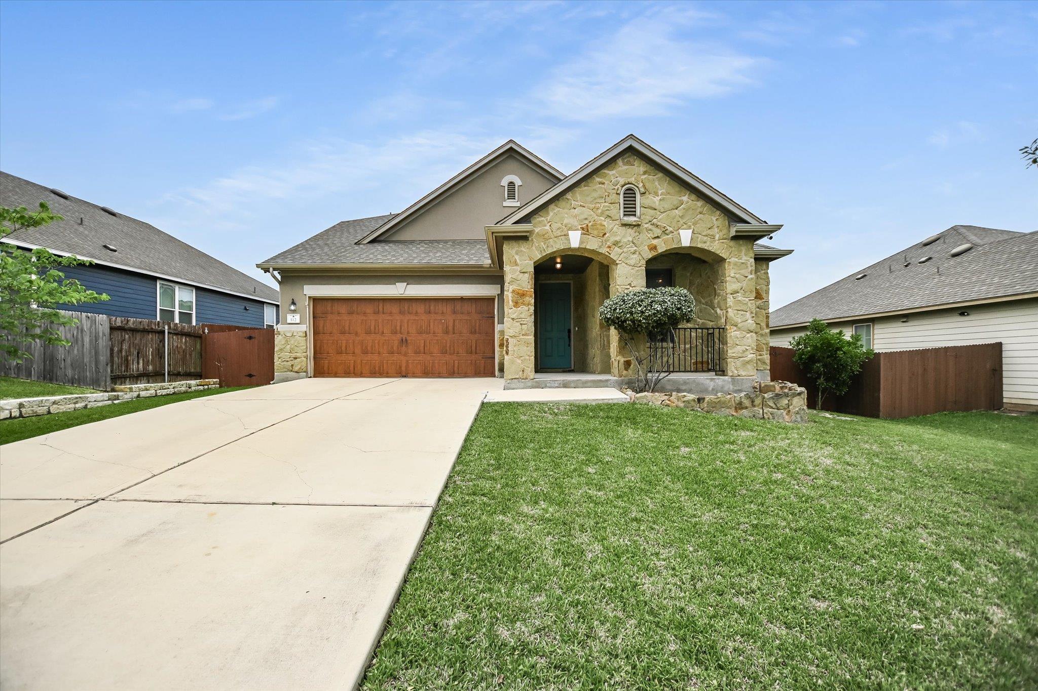 Stone and stucco facade home featuring a covered 