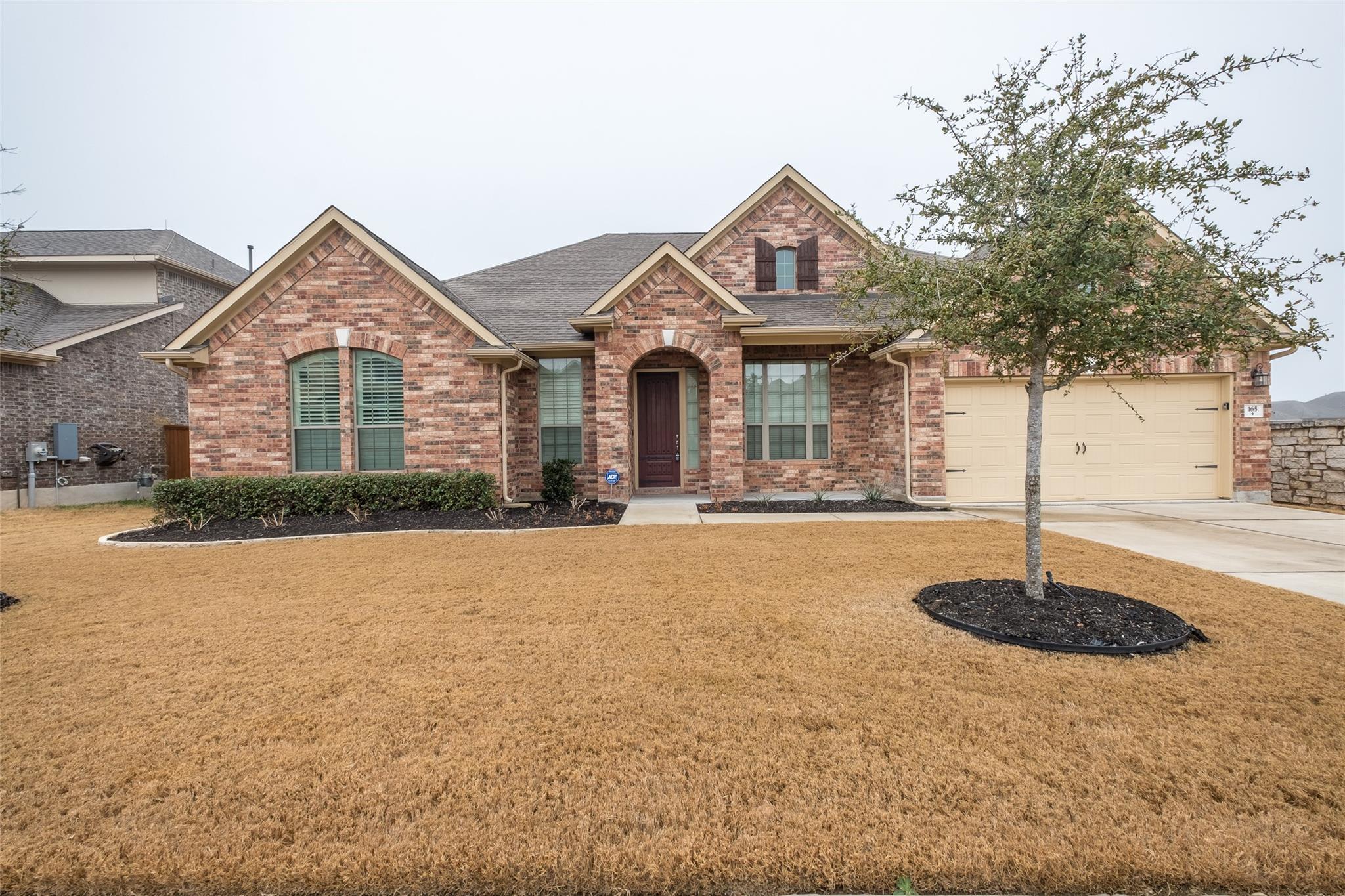 Brick facade home featuring an arched entry, a tw