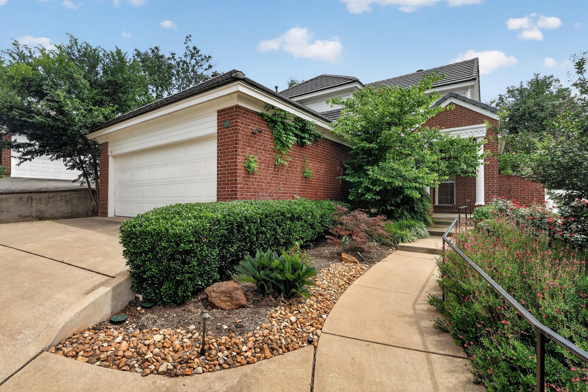 Brick facade featuring white trim, an attached ga