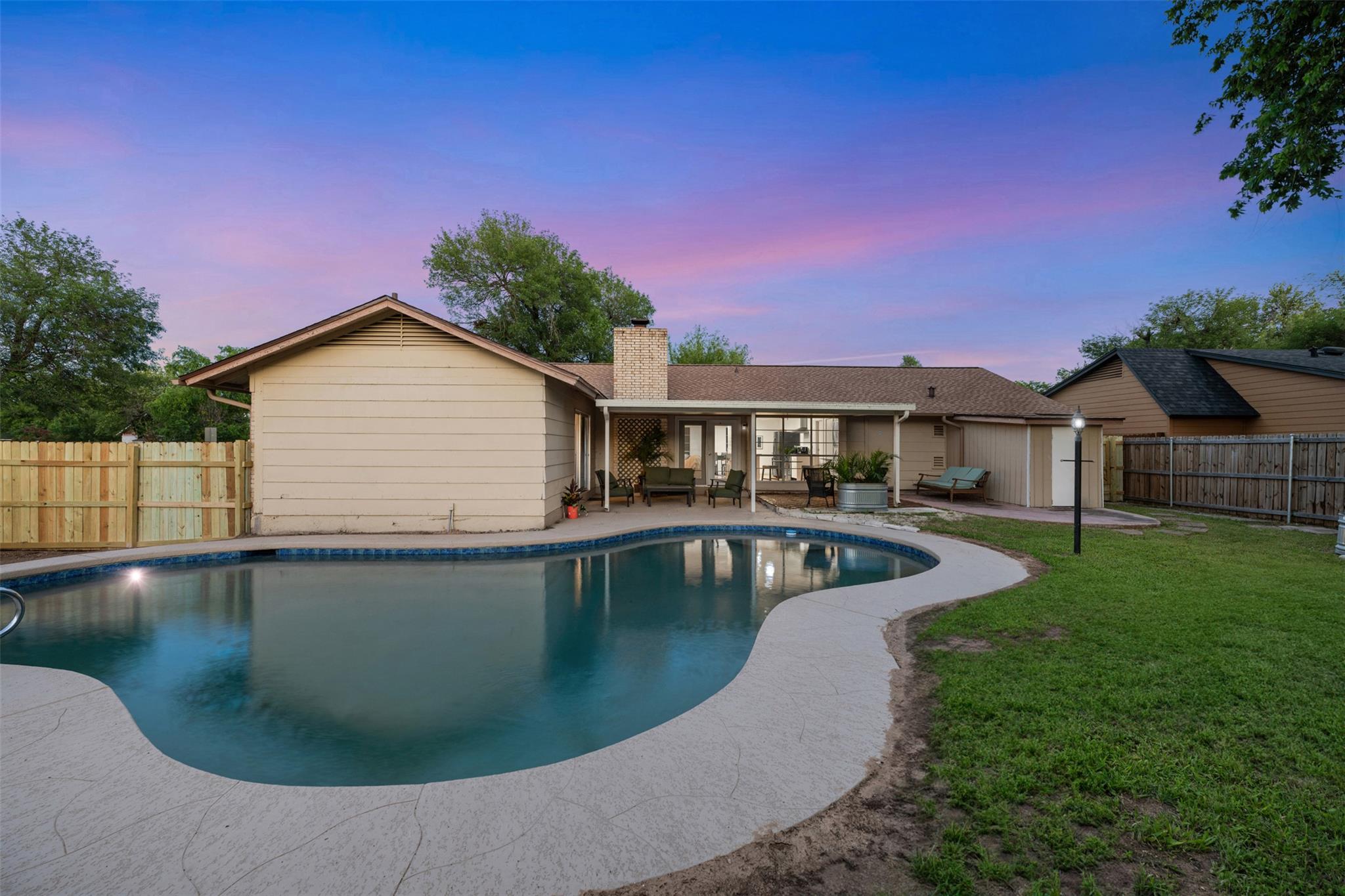 Curved in-ground swimming pool with surrounding c