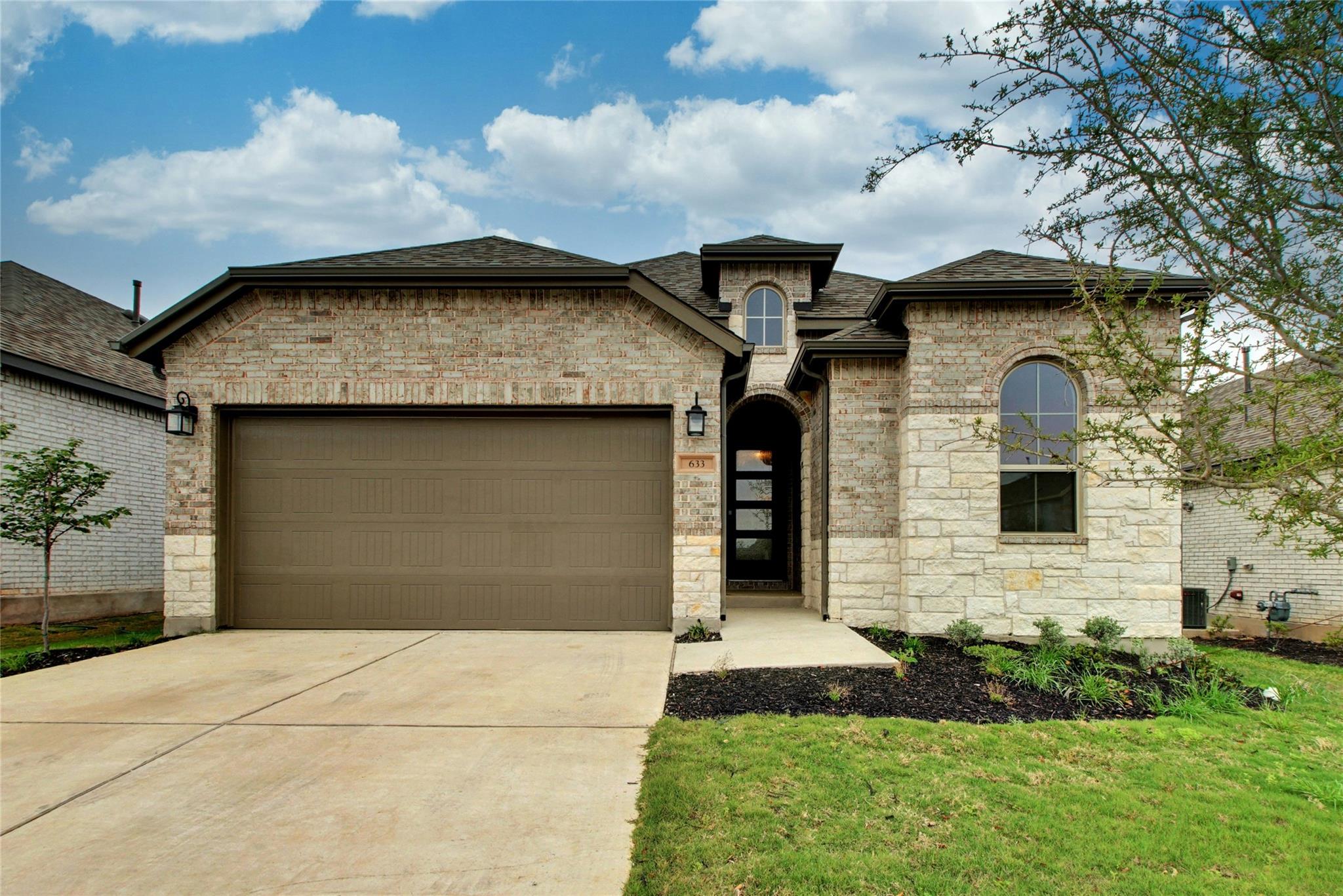 Brick and stone facade with a dark shingle roof