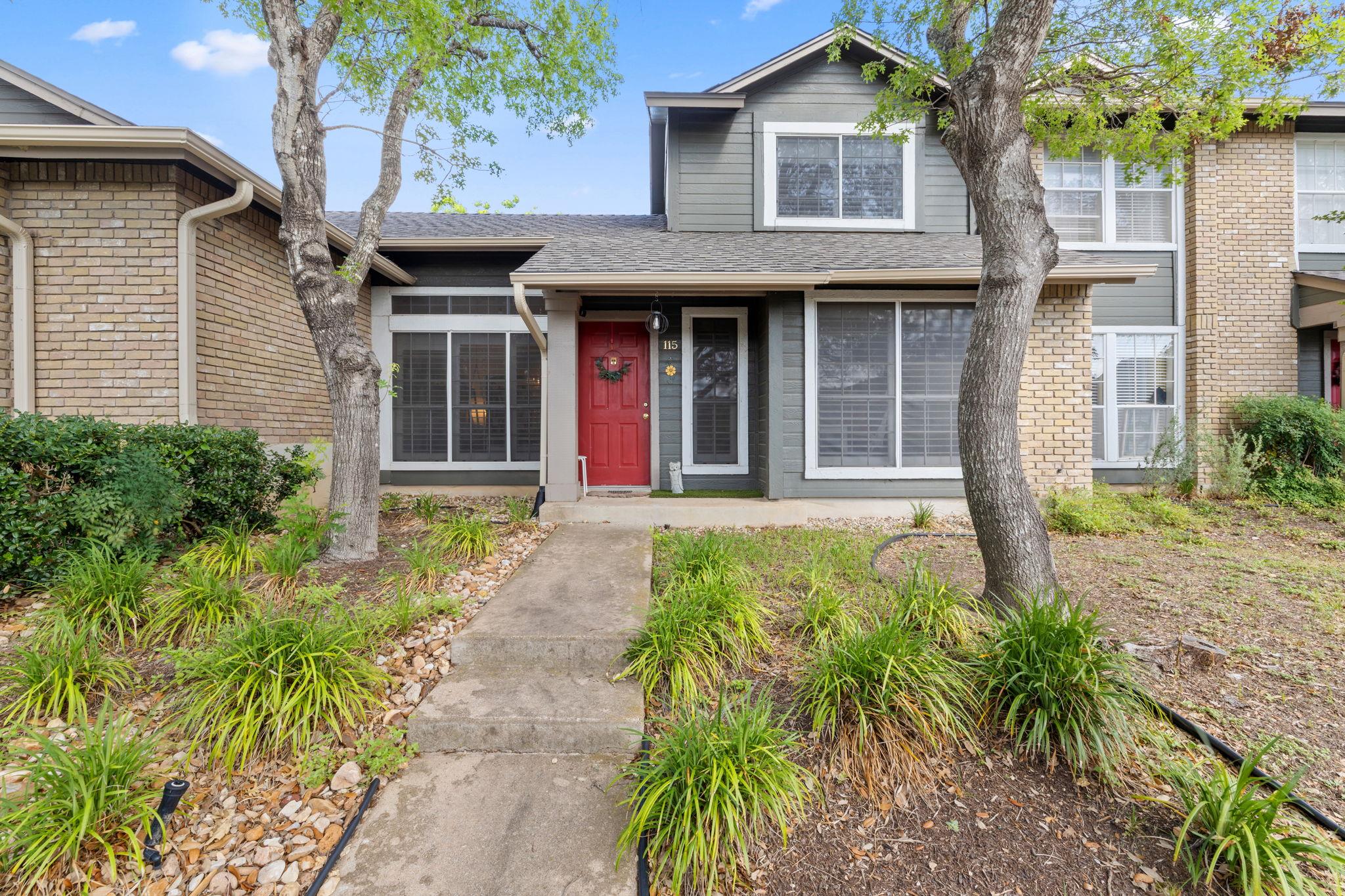Two-story exterior with a red entry door, framed 