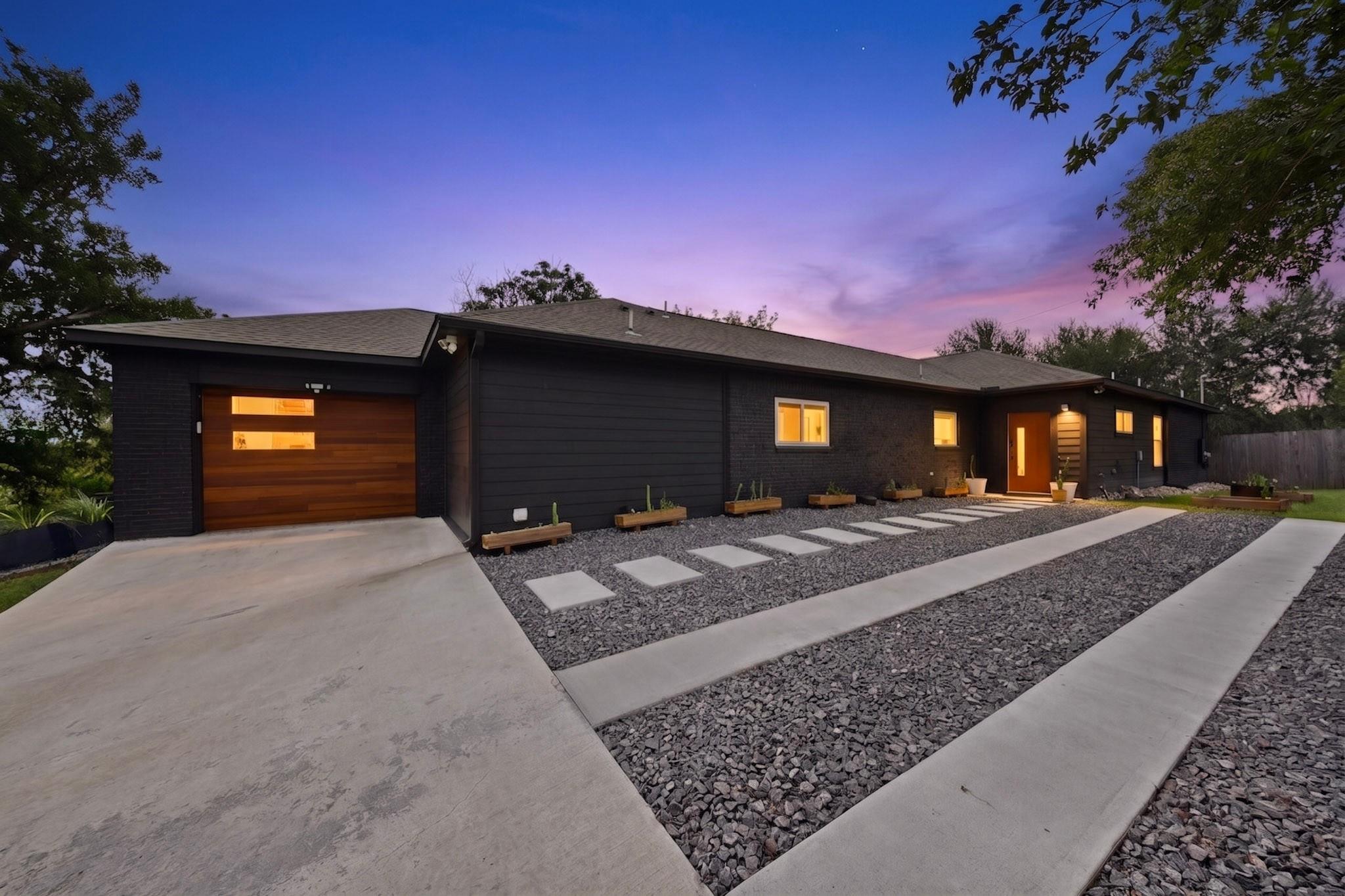 A modern home features a dark exterior, wooden ga