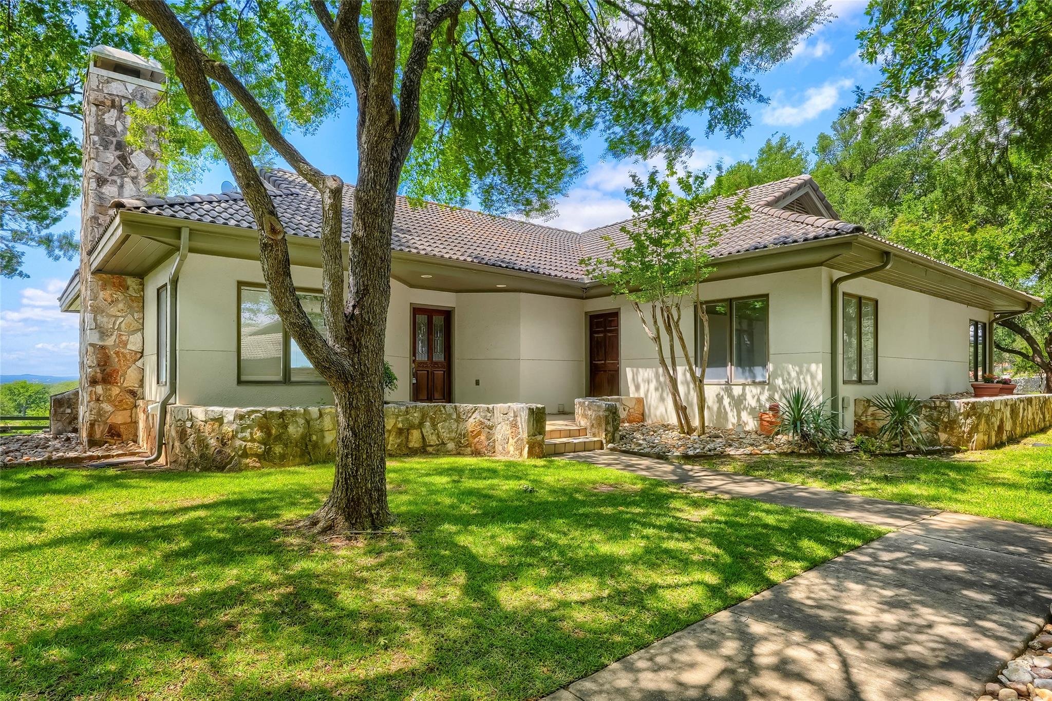 White stucco exterior with a tiled roof, stone ac