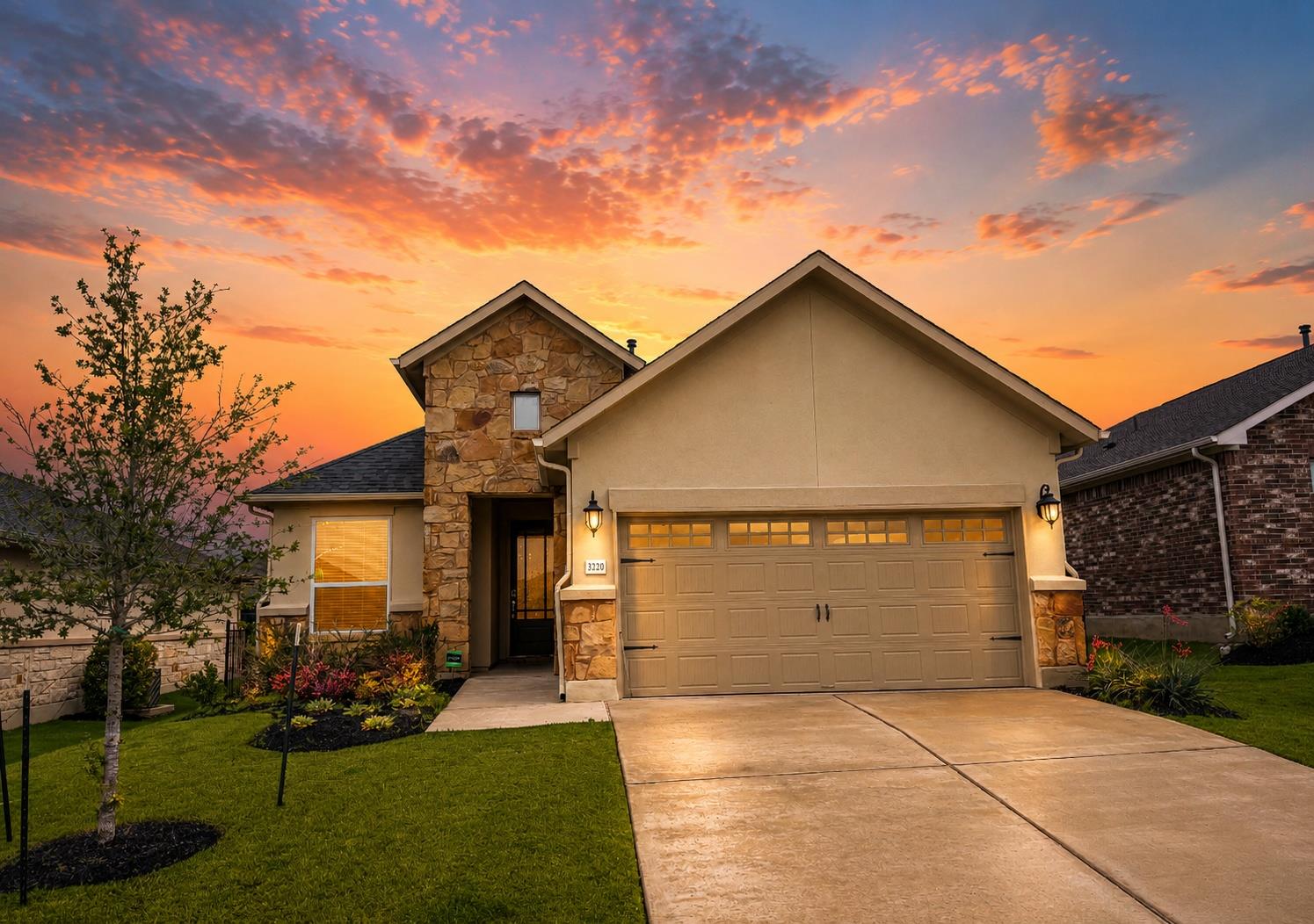 Stone and stucco exterior featuring a two-car gar