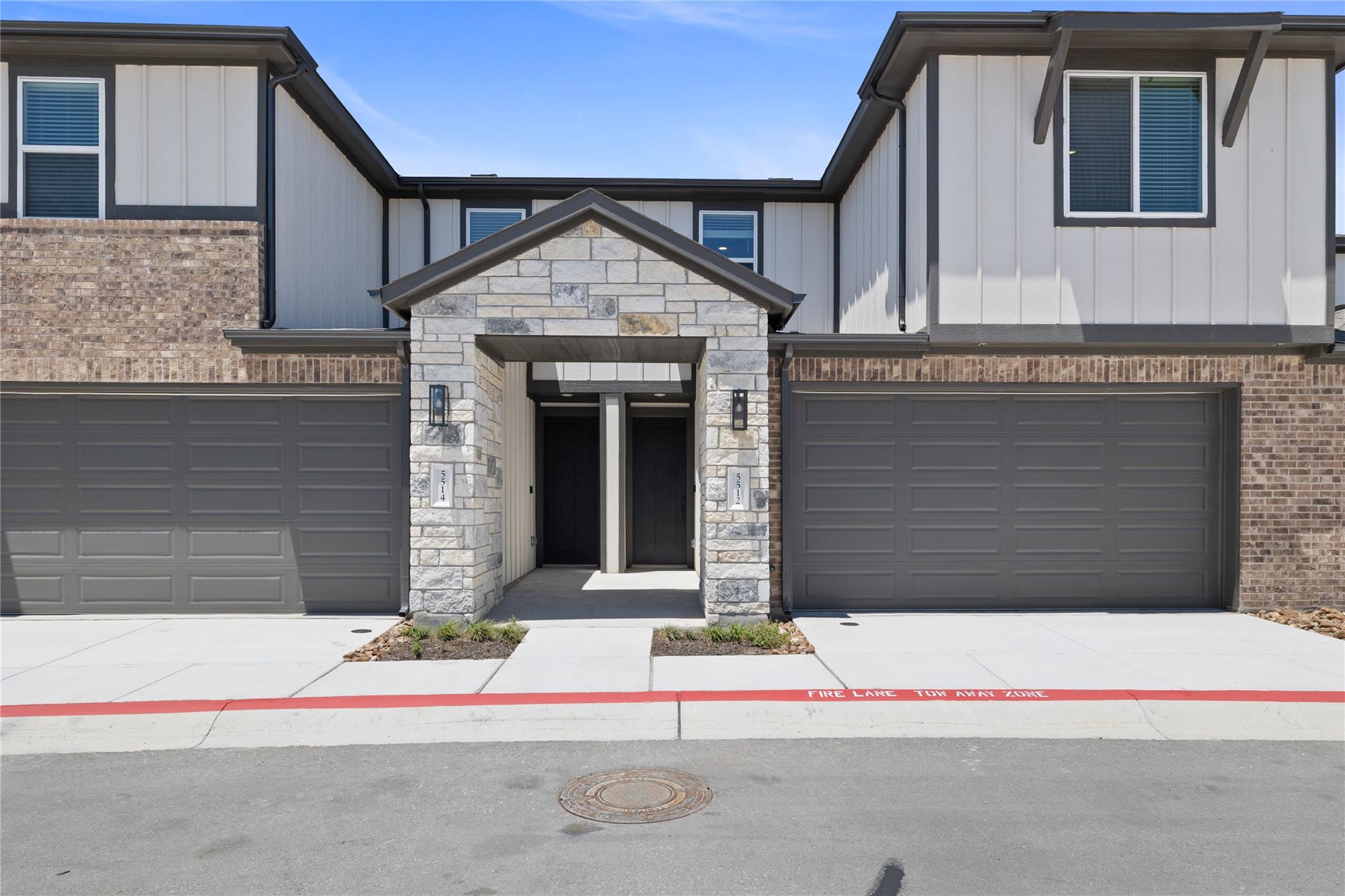 Contemporary townhome exterior featuring a stone 