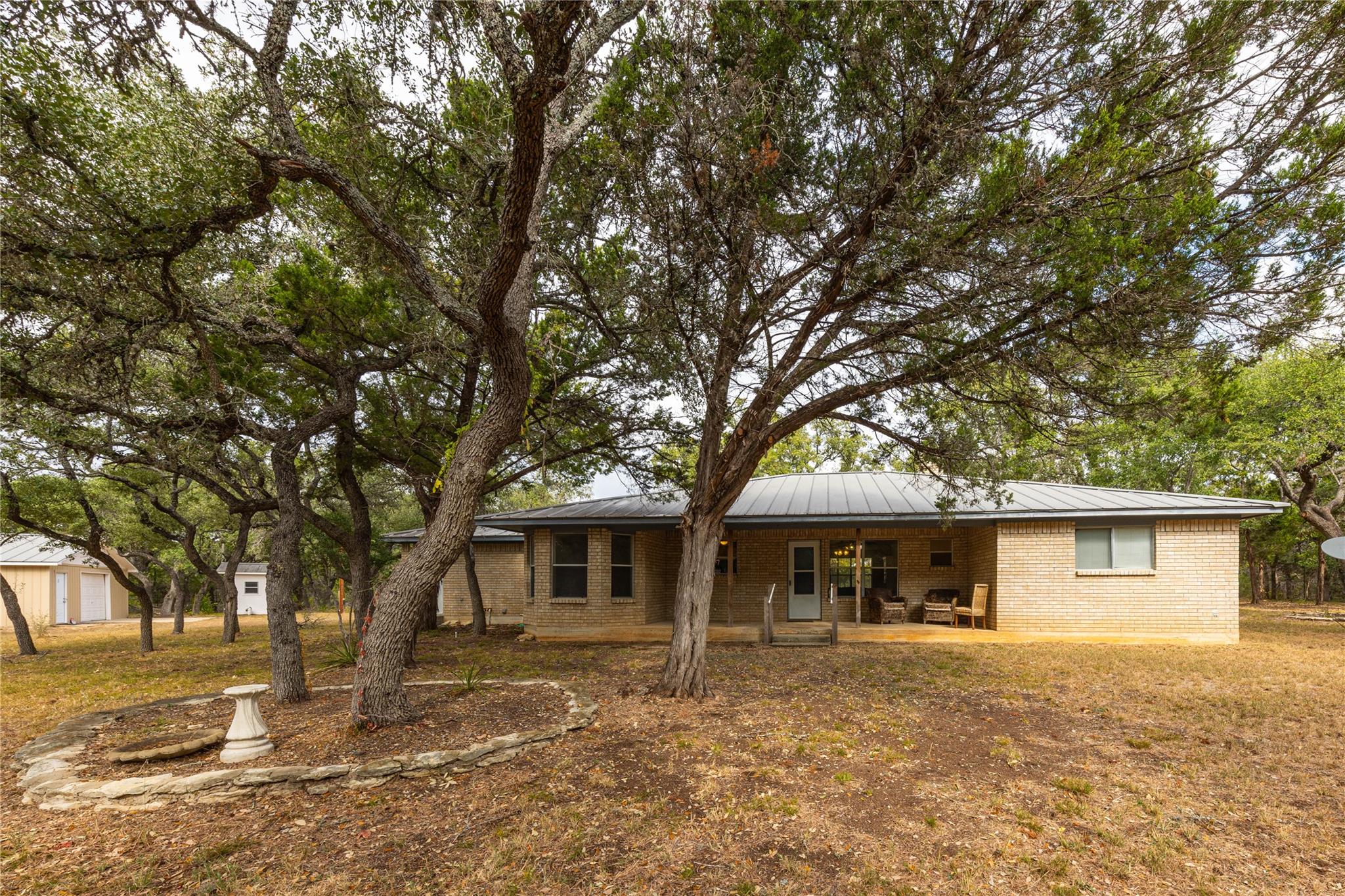 Expansive backyard featuring mature trees, a ston