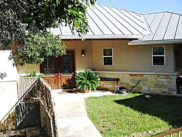 Stucco exterior featuring a metal roof, stone fac