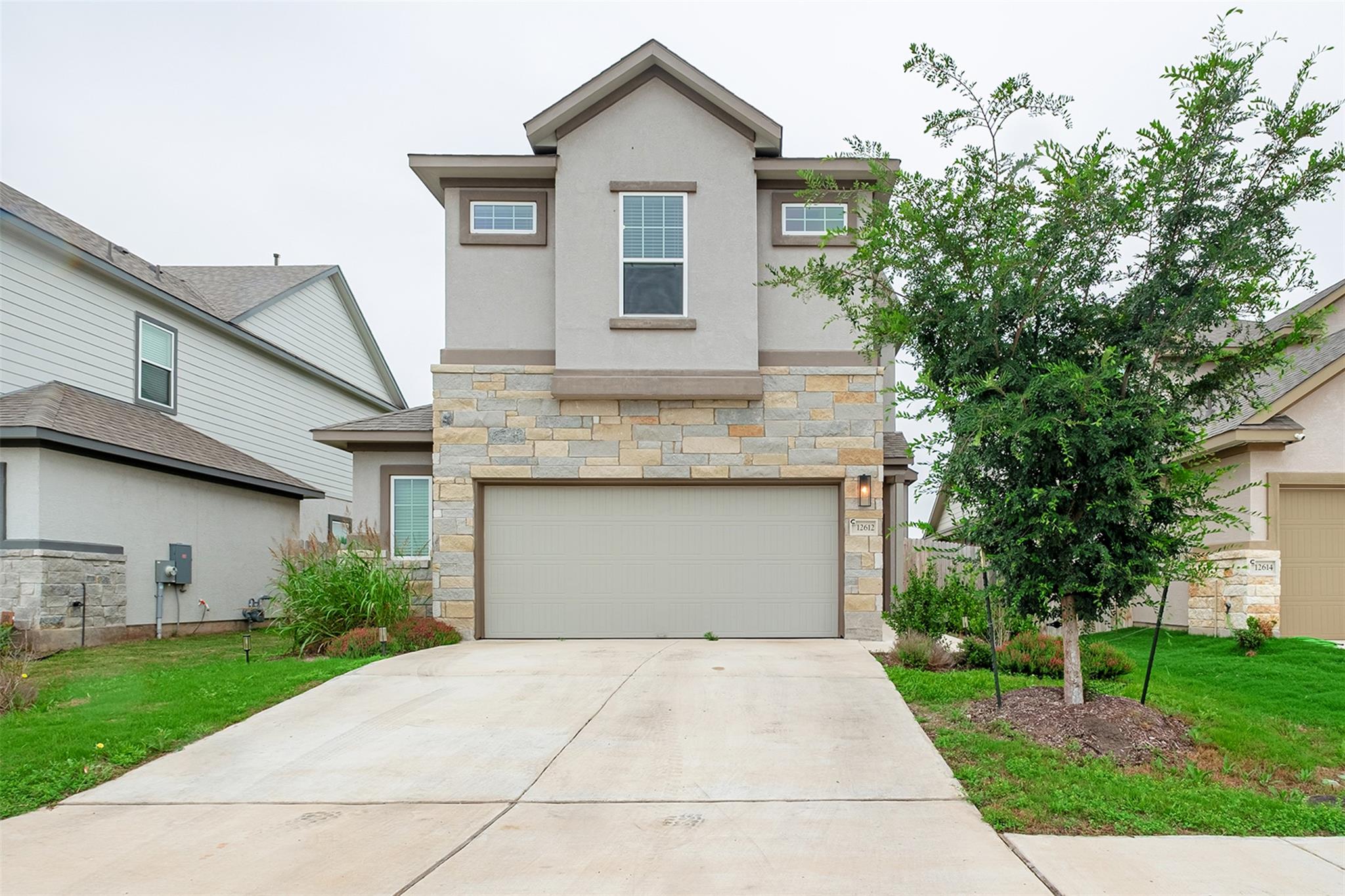 Two-story stucco and stone exterior featuring a p