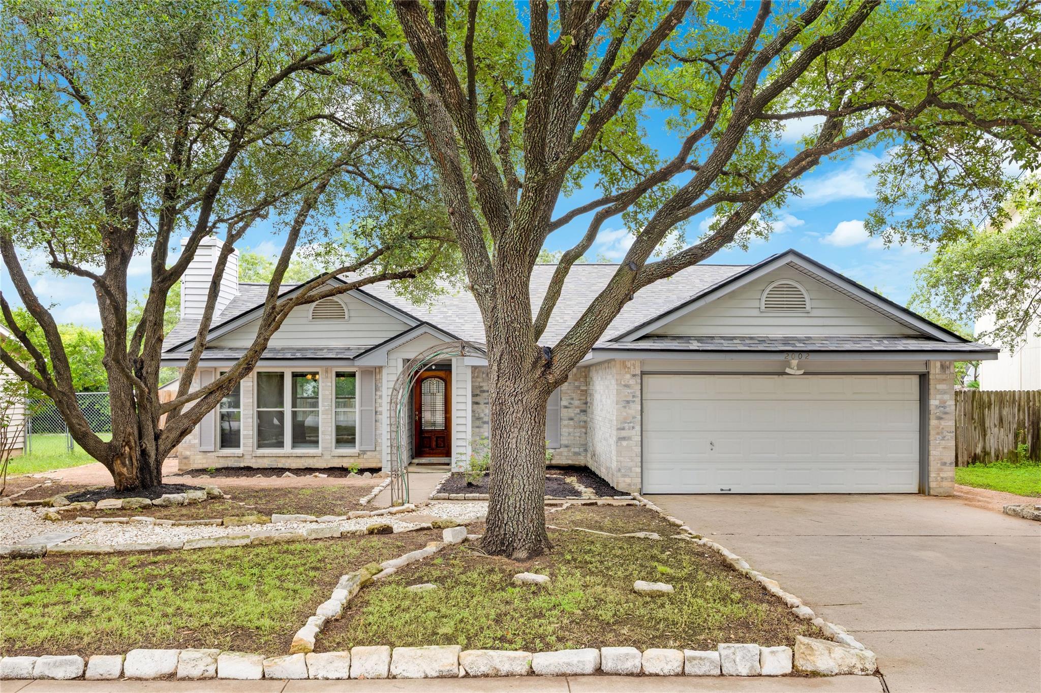Mature trees shade the front yard and entrance of