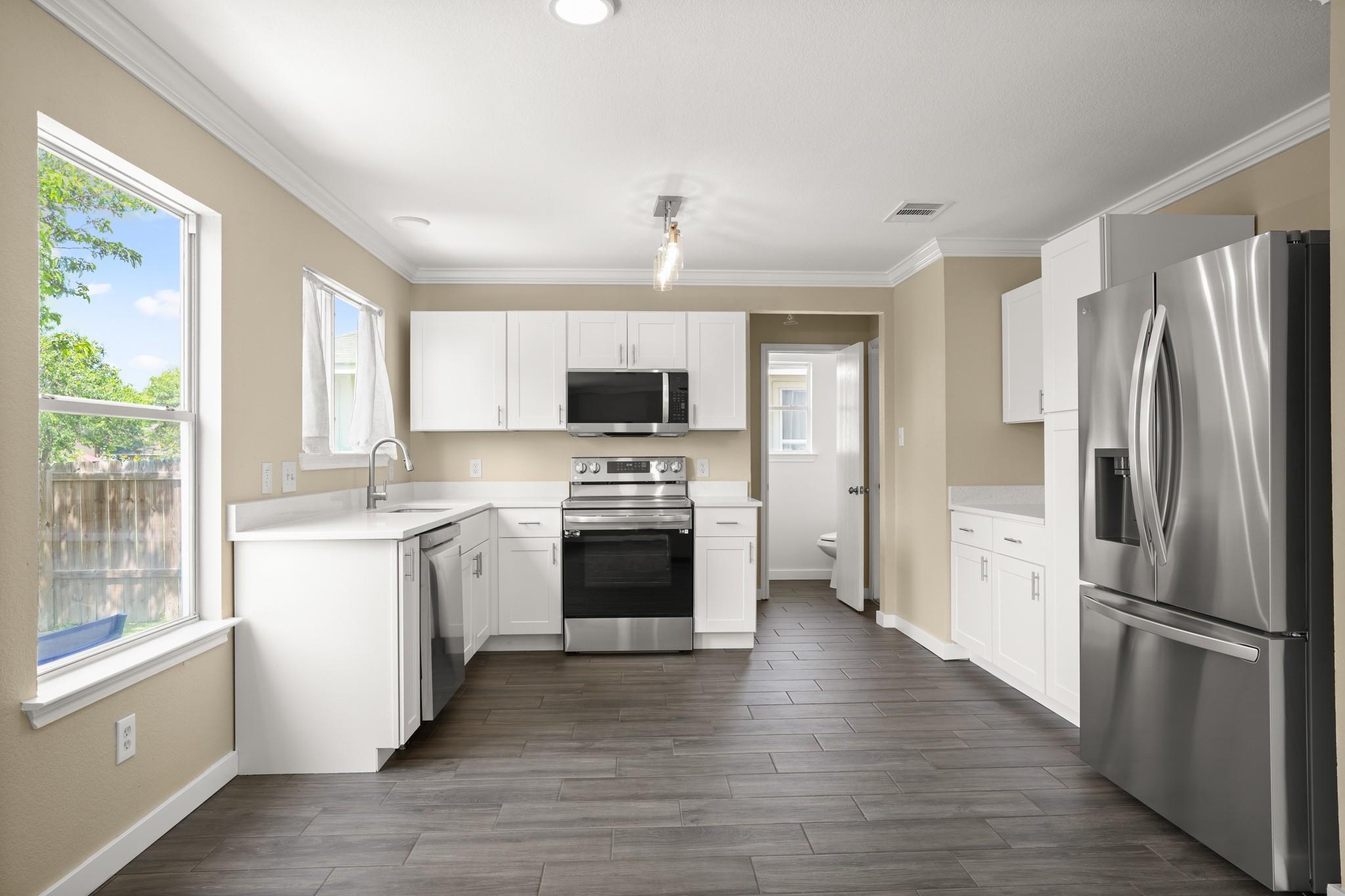 A contemporary kitchen boasts pristine white cabi